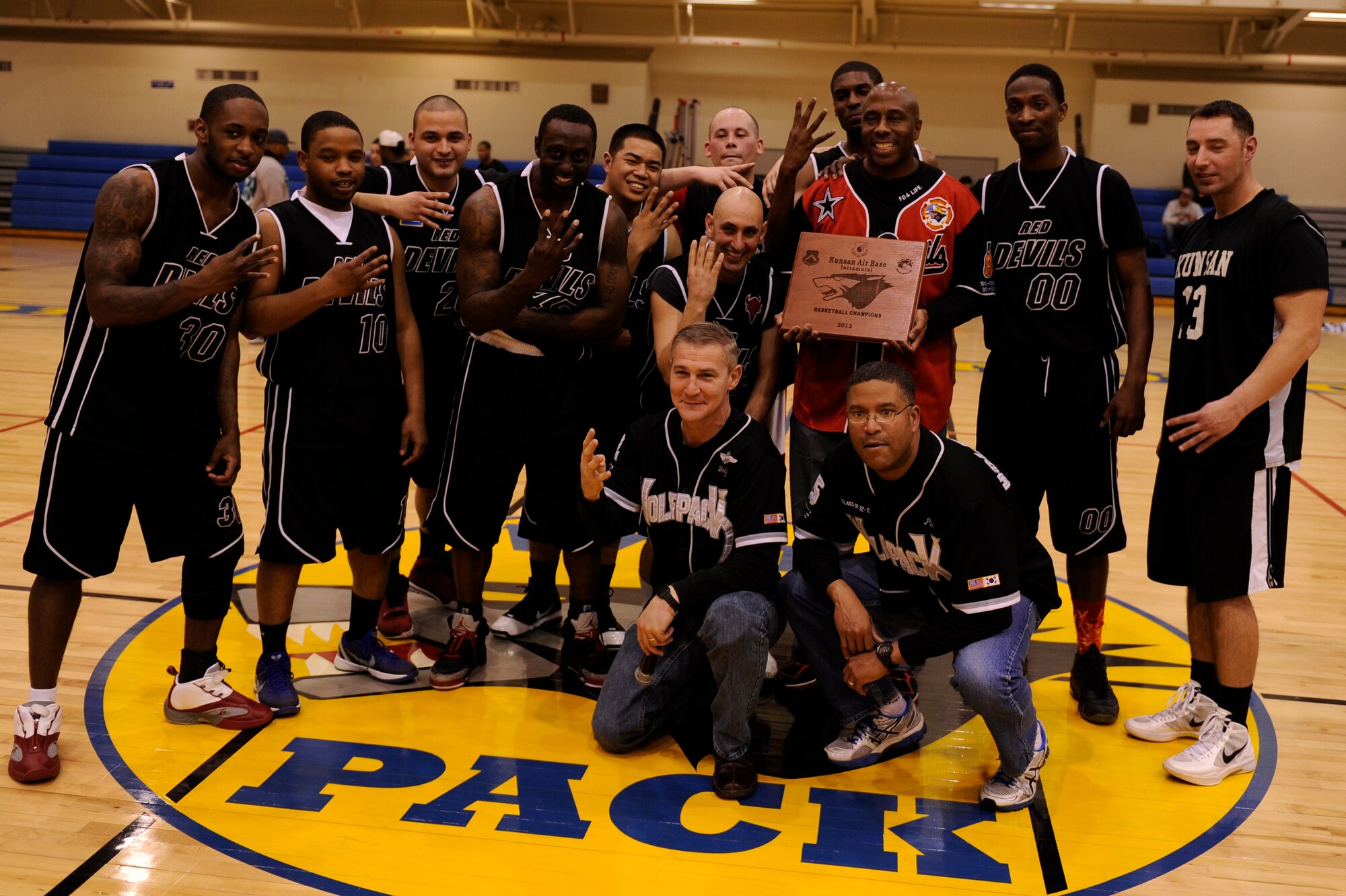 Wing leadership poses for a photo with the 8th Civil Engineer Squadron basketball team while holding up the Red Devils pitch fork sign at Kunsan Air Base, Republic of Korea, March 1, 2013. The 8th CES beat the 8th Force Support Squadron in the basketball championship, 49 to 42. (U.S. Air Force photo by Senior Airman Marcus Morris/Released)
