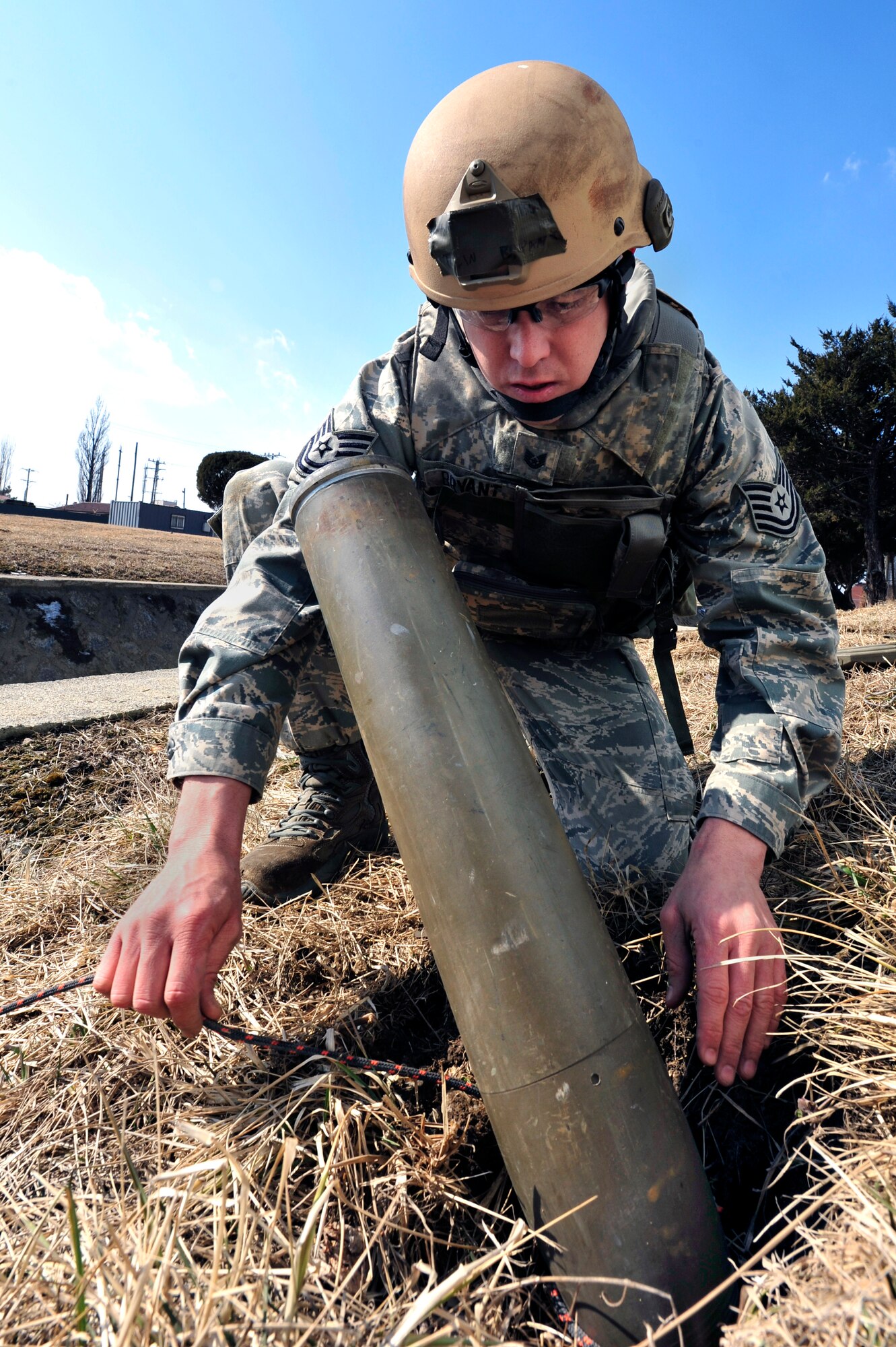 Tech. Sgt. Tobin Bryant, 51st Civil Engineer Squadron explosive ordnance disposal flight NCO in charge, connects a rope to a 130 mm rocket to pull it out of the ground in an unexploded ordnance exercise at Osan Air Base, Republic of Korea, Feb. 21, 2013. The EOD team works in groups of two or three to assess and rectify any munitions or explosive scenarios. (U.S. Air Force photo/Airman 1st Class Alexis Siekert)