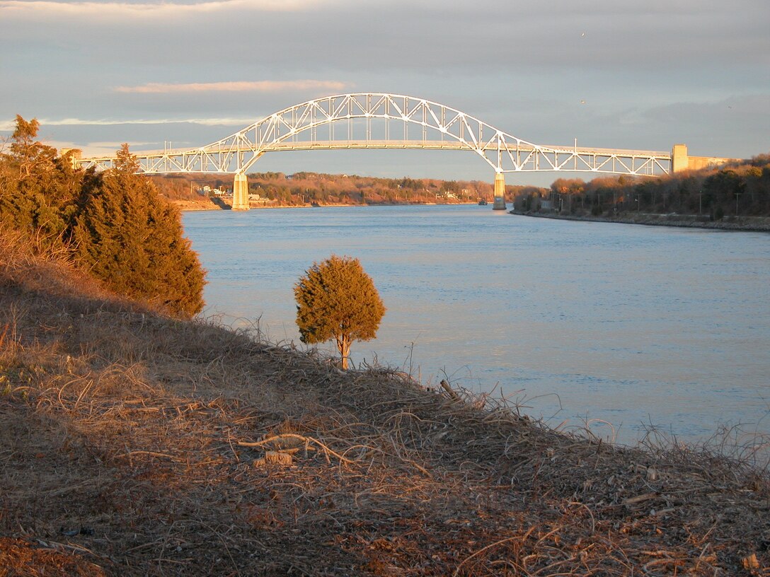 Sagamore Bridge, which spans the Cape Cod Canal, at sunset, is one of three bridges that span the canal and were designed to allow for 135 feet of vertical clearance above mean high tide. The Cape Cod Canal is the world's widest sea-level canal at 480 feet wide and has authorized depth of 32 feet at mean low water. The swift running Canal current changes direction every six hours and can reach a maximum velocity of 5.2 miles per hour, during the ebb (westerly) tide. In addition to being a preeminent navigation project, the Cape Cod Canal offers an amazing variety of recreational opportunities.