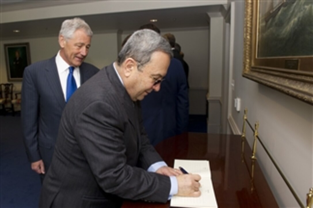 Secretary of Defense Chuck Hagel, left, watches as Israeli Minister of Defense Ehud Barak signs the guest book in the Pentagon on March 5, 2013.  Hagel and Barak are meeting to discuss national security items of interest to both nations.  