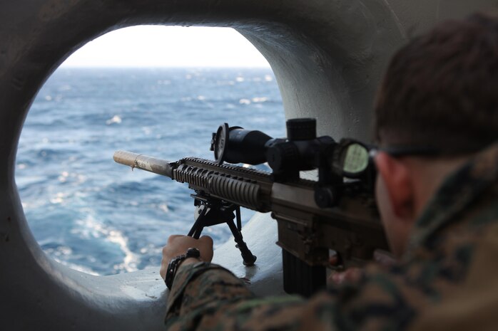 A Marine with the Maritime Raid Force, 31st Marine Expeditionary Unit, fires an M110 Semi-Automatic Sniper System rifle through a freeing port (a hole to allow water runoff) at a target from the stern of the ship here, March 6. The snipers of the 31st MEU’s Amphibious and Force Reconnaissance Platoons conducted marksmanship training to keep their skills sharp for any contingency operation that they may be called upon to execute. The 31st MEU is the only continuously forward-deployed MEU and is the Marine Corps’ force in readiness in the Asia-Pacific region.