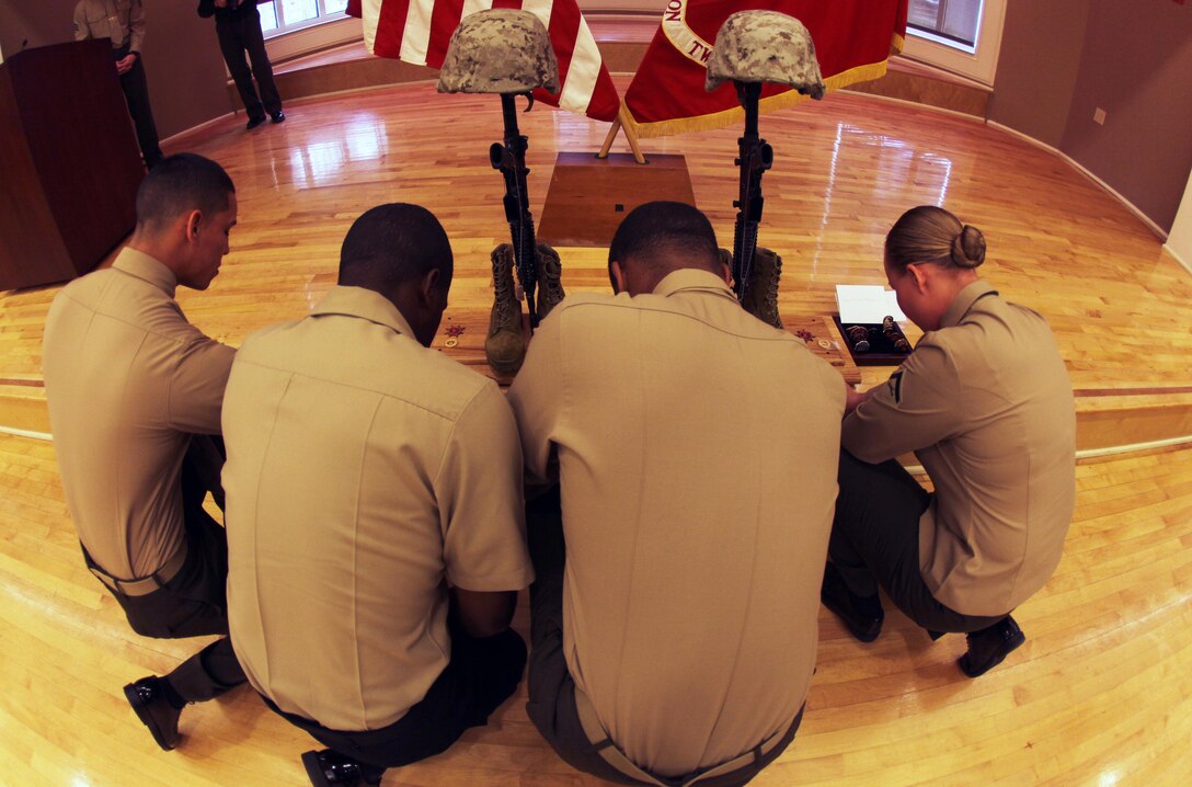 Four servicemembers kneel before a memorial set up for Cpl. Christopher M. Monahan Jr. and Lance Cpl. Dale W. Means, motor transportation operators with Combat Logistics Battalion 2, 2nd Marine Logistics Group, aboard Camp Lejeune, N.C., Feb. 22, 2013. The battalion spent nearly seven months providing tactical logistics support to units in Helmand province, Afghanistan. 