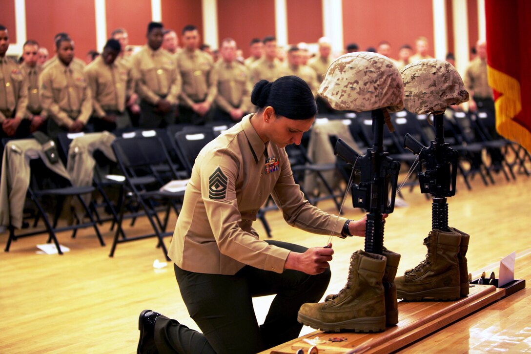A Marine pays her respects to Cpl. Christopher M. Monahan Jr. and Lance Cpl. Dale W. Means, motor transportation operators with Combat Logistics Battalion 2, 2nd Marine Logistics Group, who were killed in Helmand province, Afghanistan, November 2012. The battalion hosted a memorial ceremony to allow the families and friends to join the unit in honoring the sacrifices of the two Marines. 