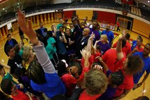 Emilio Garza (center), the principal of Brewster Middle School and a native of Del Rio, Texas, participates in a team cheer with the players and coaches of the Hoops-N-Dreams program aboard Camp Lejeune, N.C., Feb. 22, 2013. Garza and other supporters from across the base came together for the program’s jamboree, where four teams of students engaged in an evening of friendly basketball and team building activities. 