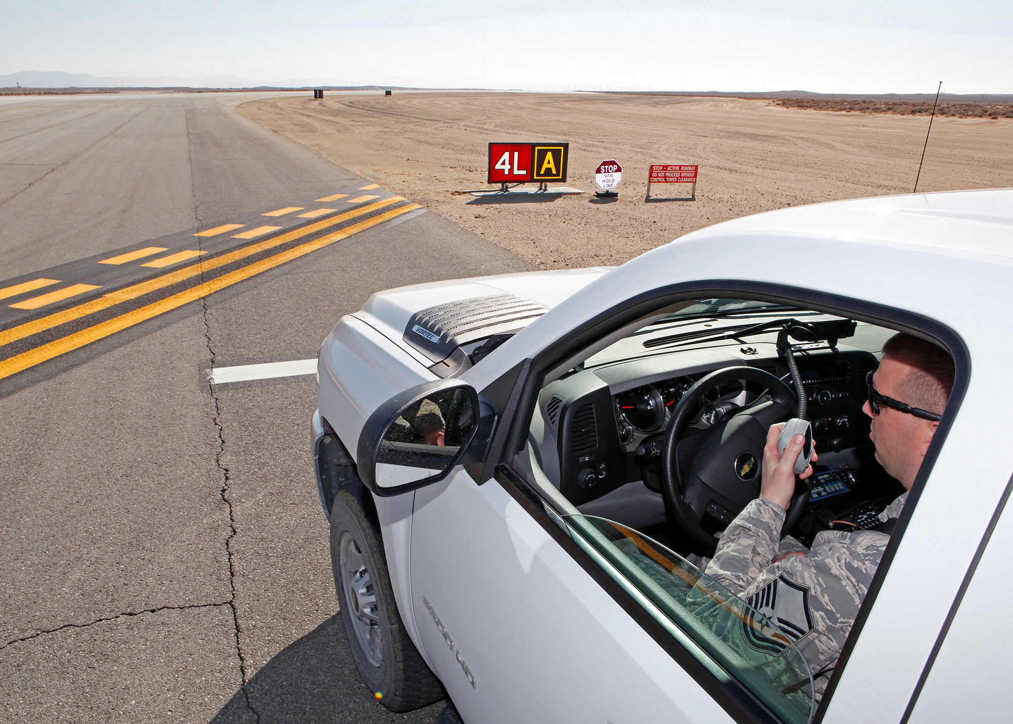 Master Sgt. William DeAngel, 412th Operations Support Squadron deputy airfield manager, demonstrates the proper way of contacting the air traffic control tower for clearance to drive on the airfield runway while waiting on the runway hold line March 5 at Edwards Air Force Base. (U.S. Air Force photo by Jet Fabara)