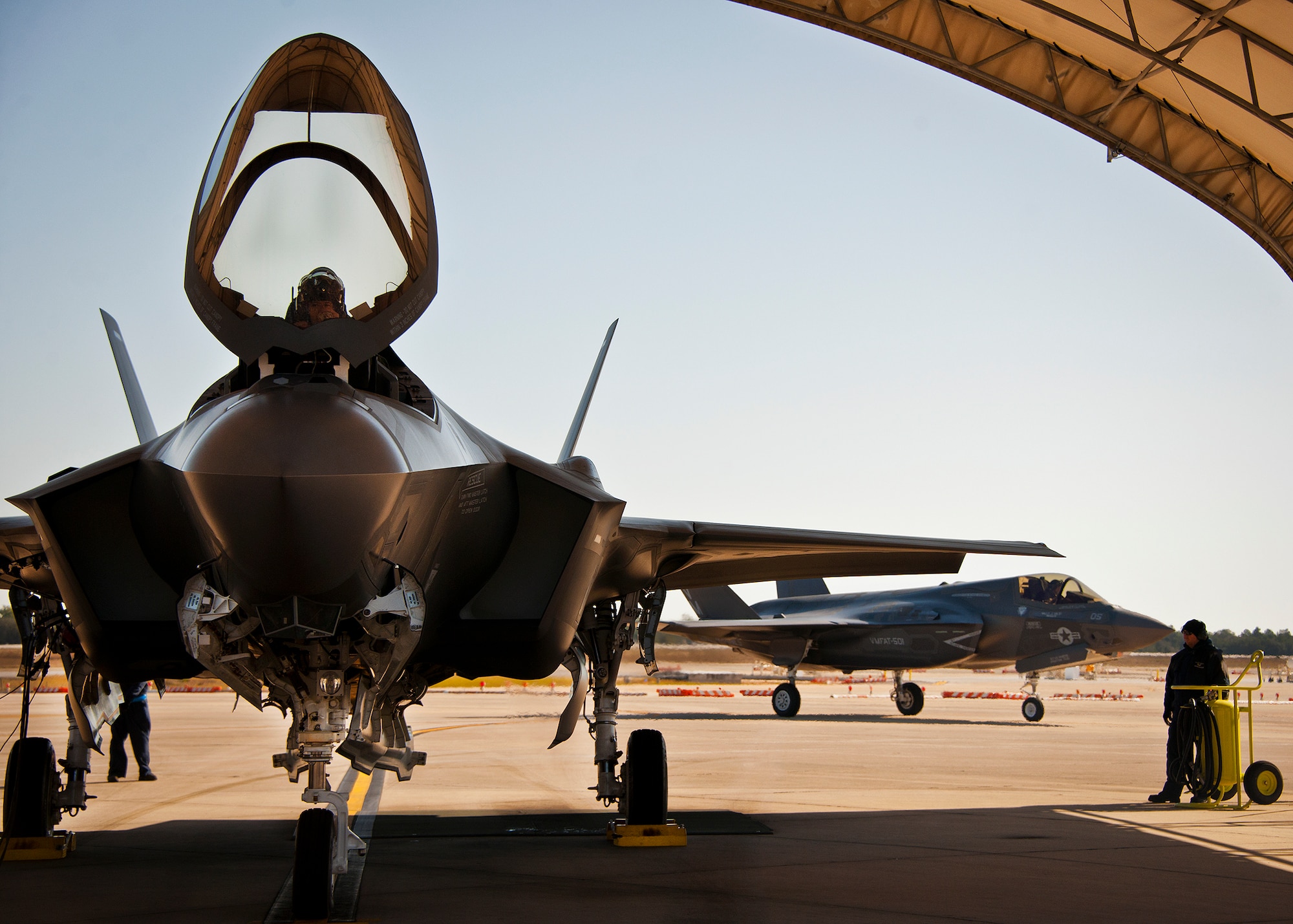 Lt. Col. Benjamin Bishop, the 422nd Test and Evaluation Squadron director of operations, completes preflight checks before his first sortie in an F-35A Lightning II as an F-35B rolls past at Eglin Air Force Base, Fla., March 6.  Bishop is among the first pilots to begin the official training that began in January.  Bishop and other 422nd TES pilots will begin operational testing of the joint strike fighter later this year at Nellis Air Force Base, Nev.  (U.S. Air Force photo/Samuel King Jr.)