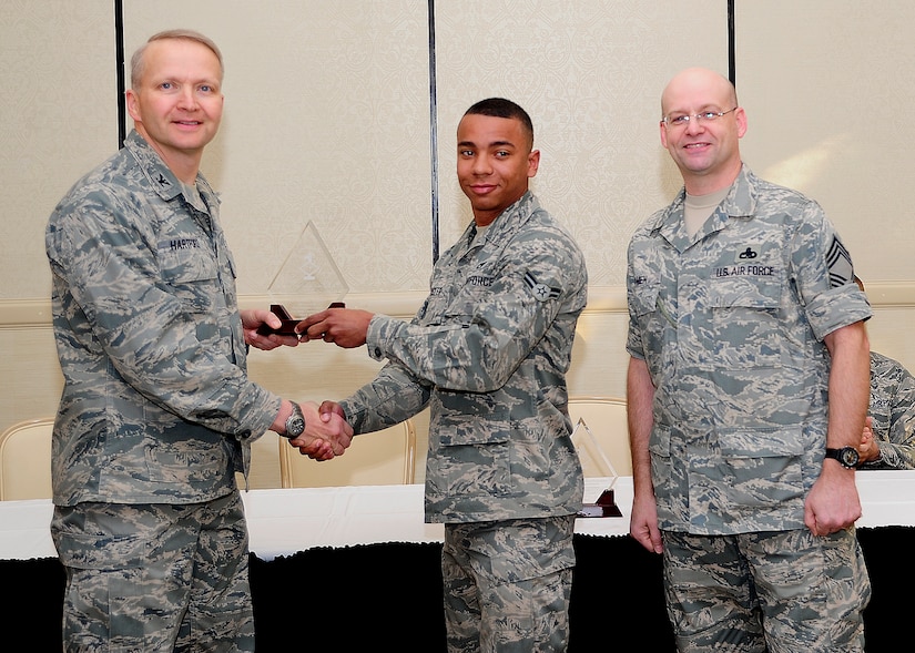 Colonel Darren Hartford, 437th Airlift Wing commander, and Chief Master Sgt. Gerard Komen, 437th Maintenance Operations Squadron superintendent, congratulate Airman First Class Gregory Foster, 437th Aerial Port Squadron passenger services agent, as a Diamond Sharp award winner during a ceremony March 5, 2013, at the Charleston Club at Joint Base Charleston - Air Base, S.C. Diamond Sharp awardees are Airmen chosen by their first sergeants for their excellent performance. (U.S. Air Force photo/ Staff Sgt. Rasheen Douglas)