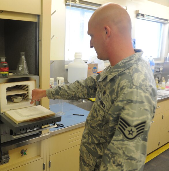 Staff Sgt. Paul Bauer, 9th Civil Engineer Squadron water and fuels system maintenance journeyman, prepares to heat a sample of bio-solid in a furnace at 550 degrees Celsius at the waste water facility on Beale Air Force Base, Calif., March 5, 2013. The scientific process burns off volatile solids in the sample. (U.S. Air Force photo by Airman 1st Class Bobby Cummings/Released)