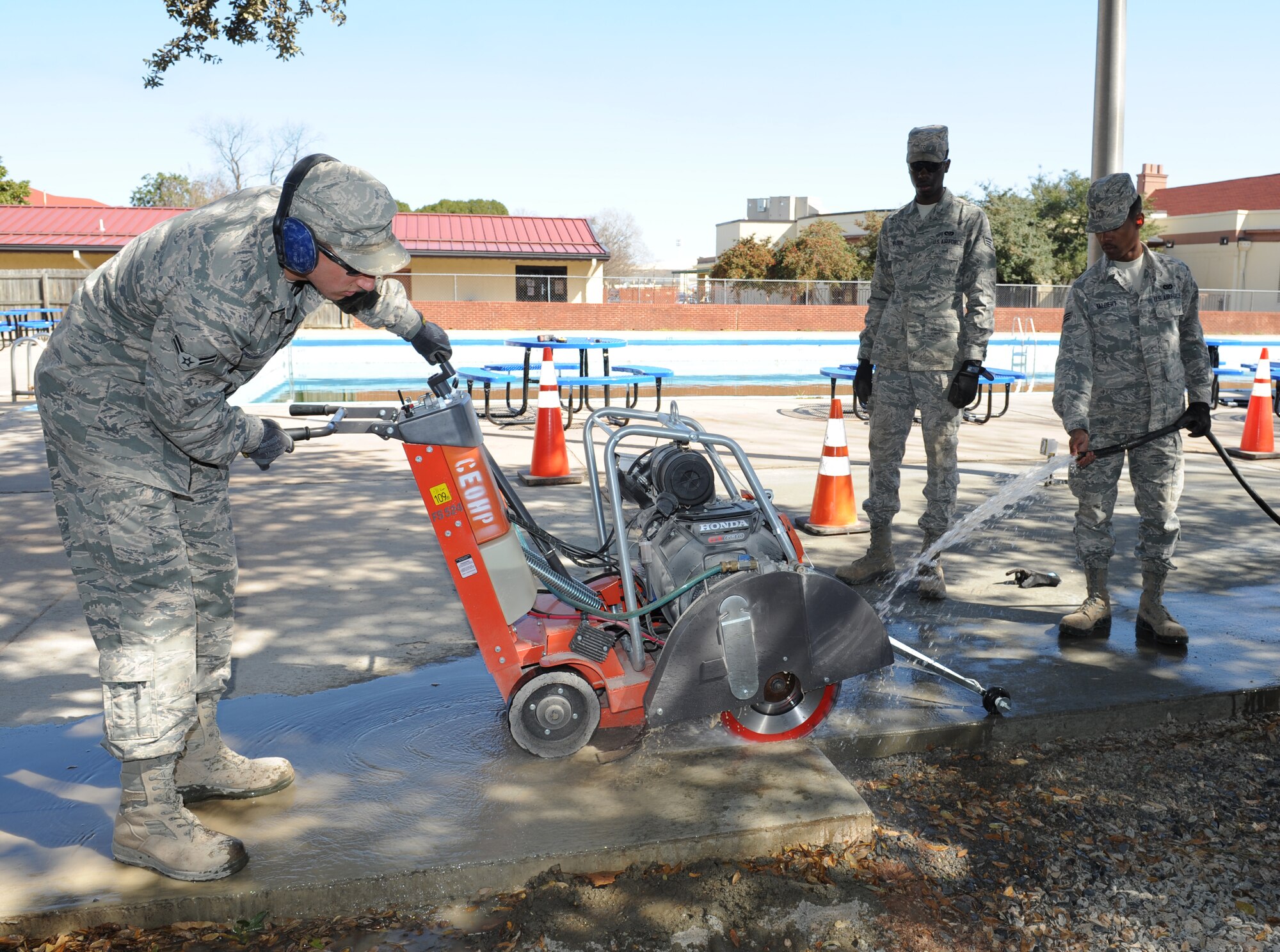 Airman 1st Class Cameron Kruell, 2nd Civil Engineer Squadron Heavy Repair Section, operates a walk behind saw while Senior Airman Trevor Talbert, 307th Rapid Engineer Deployable Heavy Operational Repair Squadron Engineers, sprays water on the saw on Barksdale Air Force Base, La., March 6. Water is sprayed on the saw to contain the amount of dust and to cool down the blade. (U.S. Air Force photo/Airman 1st Class Benjamin Gonsier)
