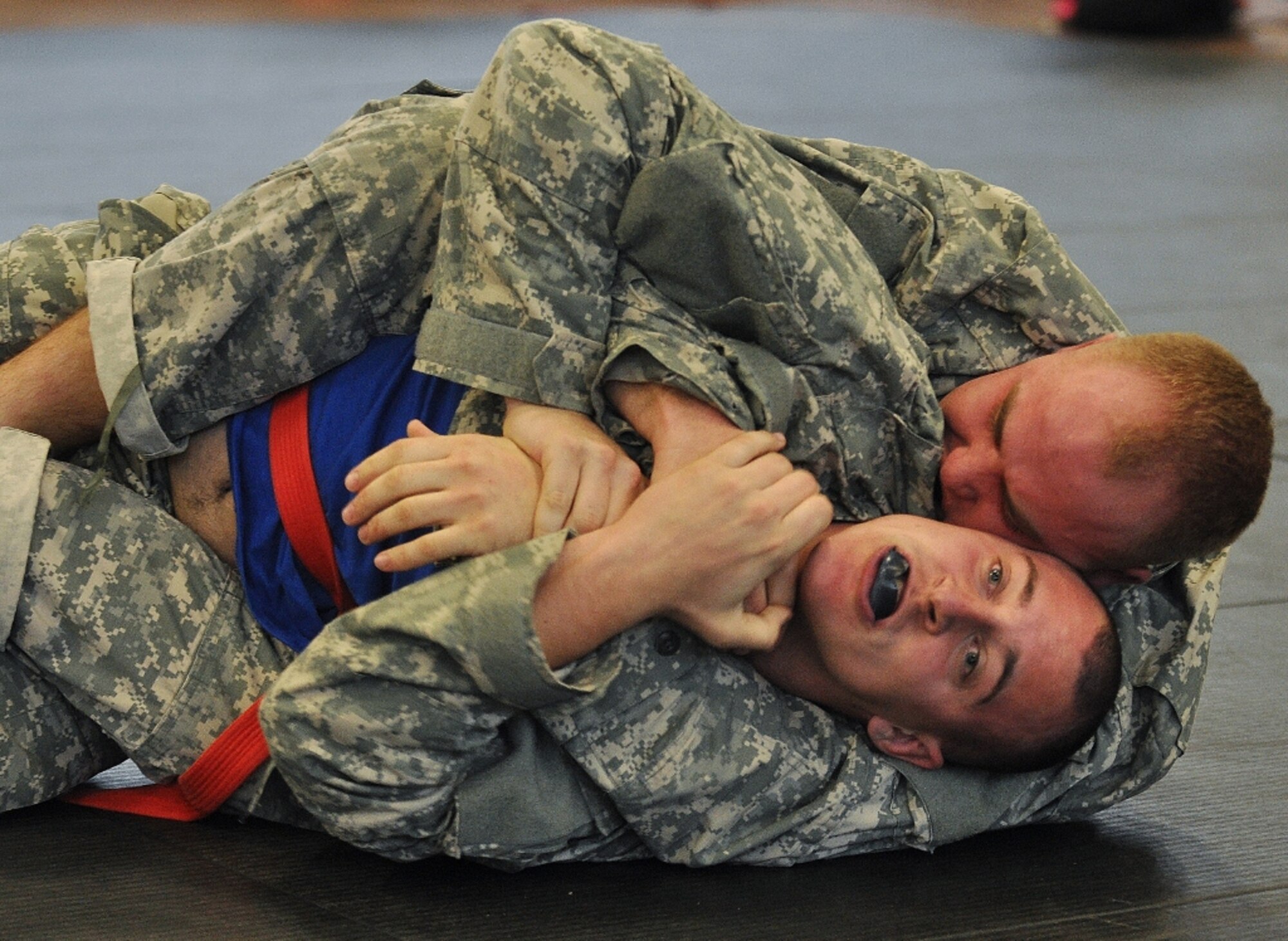 U.S. Army Pfc. Nick Reddell (wearing black mouth guard), assigned to A Company, attempts to free himself from D Co.'s Pvt. Kyle Post in the heavyweight class final match during the 1st Battalion, 222nd Aviation Regiment's biannual combatives tournament at Anderson Field House at Fort Eustis, Va., Feb. 23, 2013. More than 1,200 Soldiers and guests, mostly Advanced Individual Training students from the battalion's five companies, packed the gymnasium to watch the tournament. (U.S. Air Force photo by Senior Airman Jason J. Brown/Released)
