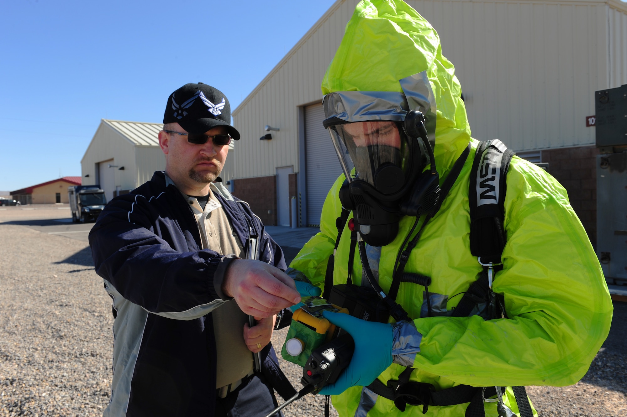 Ryan Fictum, Alliance Solutions Group, Inc., senior environmental safety and health specialist, uses cards to change the readings on Senior Airman Nicholas Johnson's, 99th Medical Group, bioenvironmental engineer journeymen, MultiRae during a simulated chemical spill Feb. 28, 2013 at Nellis Air Force Base, Nev. Spontaneously changing the recordings on the MultiRae simulates how the amount of toxins vary during a real disaster. (U.S. Air Force photo by Staff Sgt. William P. Coleman)  

