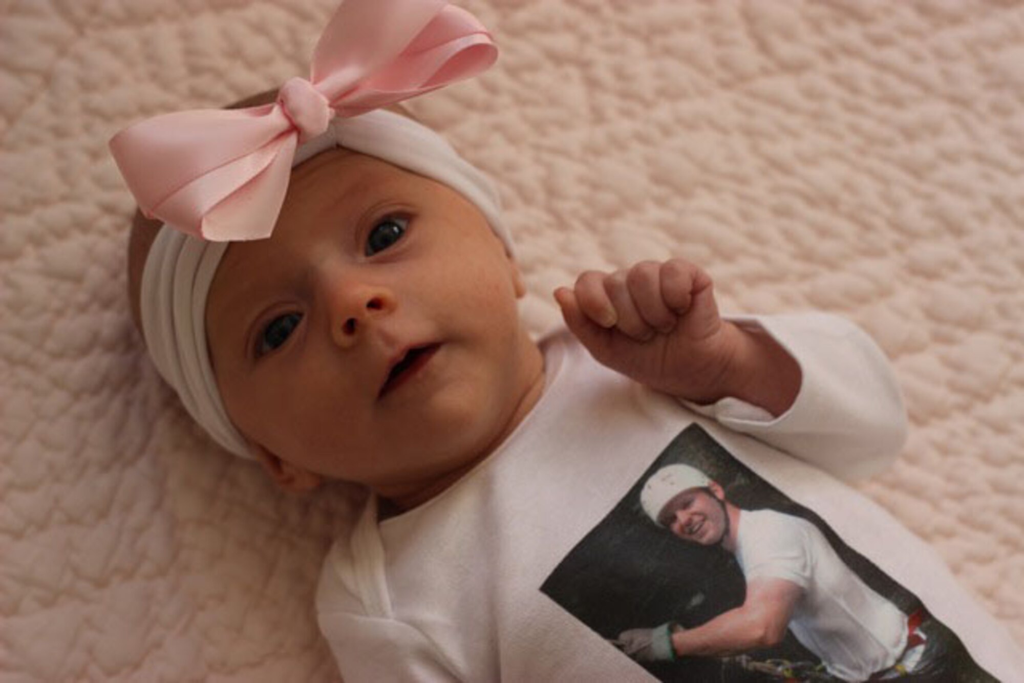 HANSCOM AIR FORCE BASE, Mass. – Riley Wilson poses in a onesie that was made by the Hanscom Airman and Family Readiness Center as part of the Readiness Emergency Sleeping Tools program. The program transfers a photo of a deployed loved one onto a keepsake for the family. (Courtesy photo)