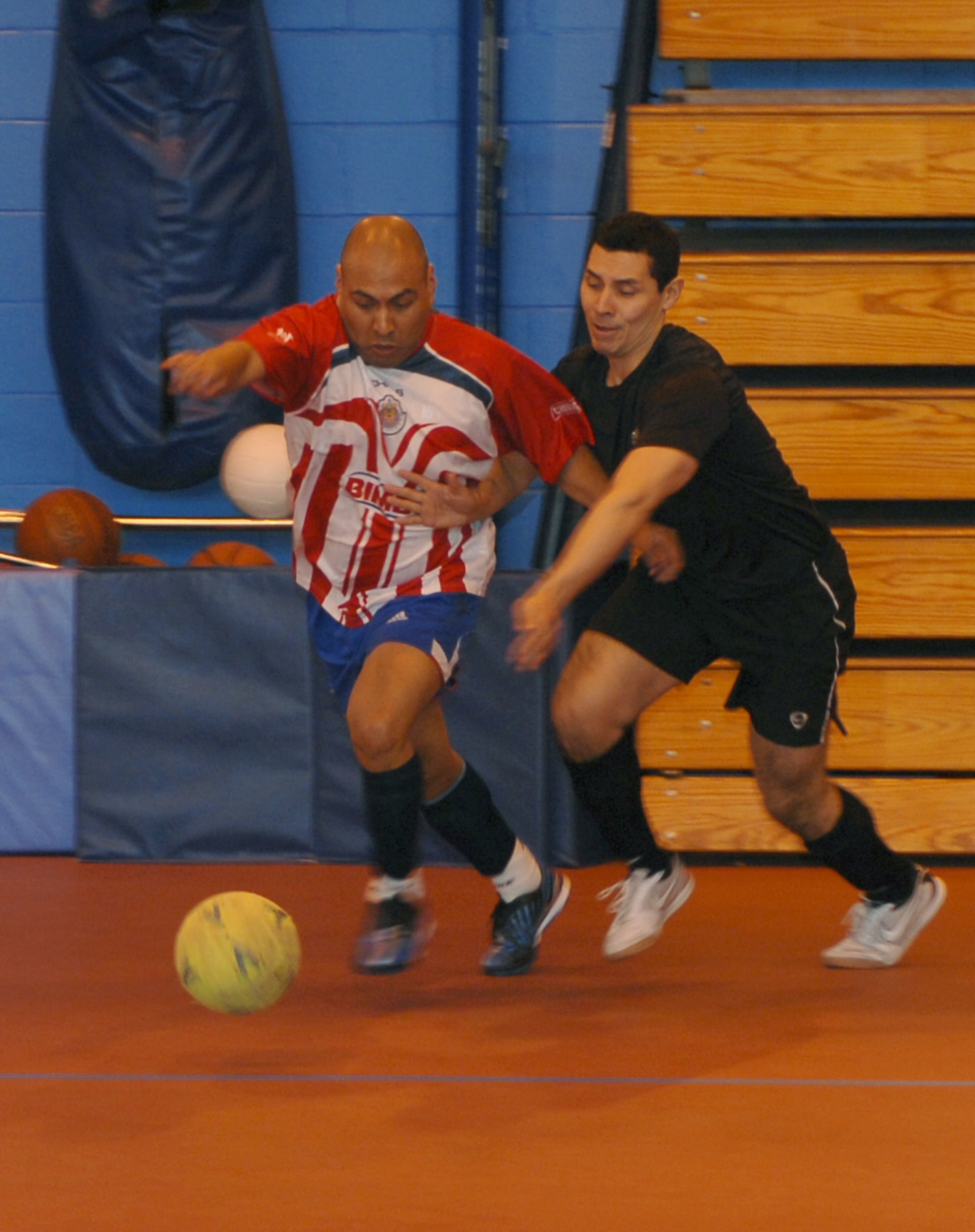 From left, Tech. Sgt. Javier Romero, 100th Force Support Squadron Fitness Center operations manager, tussles for the ball with Maj. Jose Zambrano, 95th Reconnaissance Squadron director of staff, during an indoor soccer match March 5, 2013, at the Northside Fitness Center, RAF Mildenhall, England. Romero scored two goals in the second half to give his team a narrow 3-2 win. (U.S. Air Force photo by Airman 1st Class Dillon Johnston/Released)