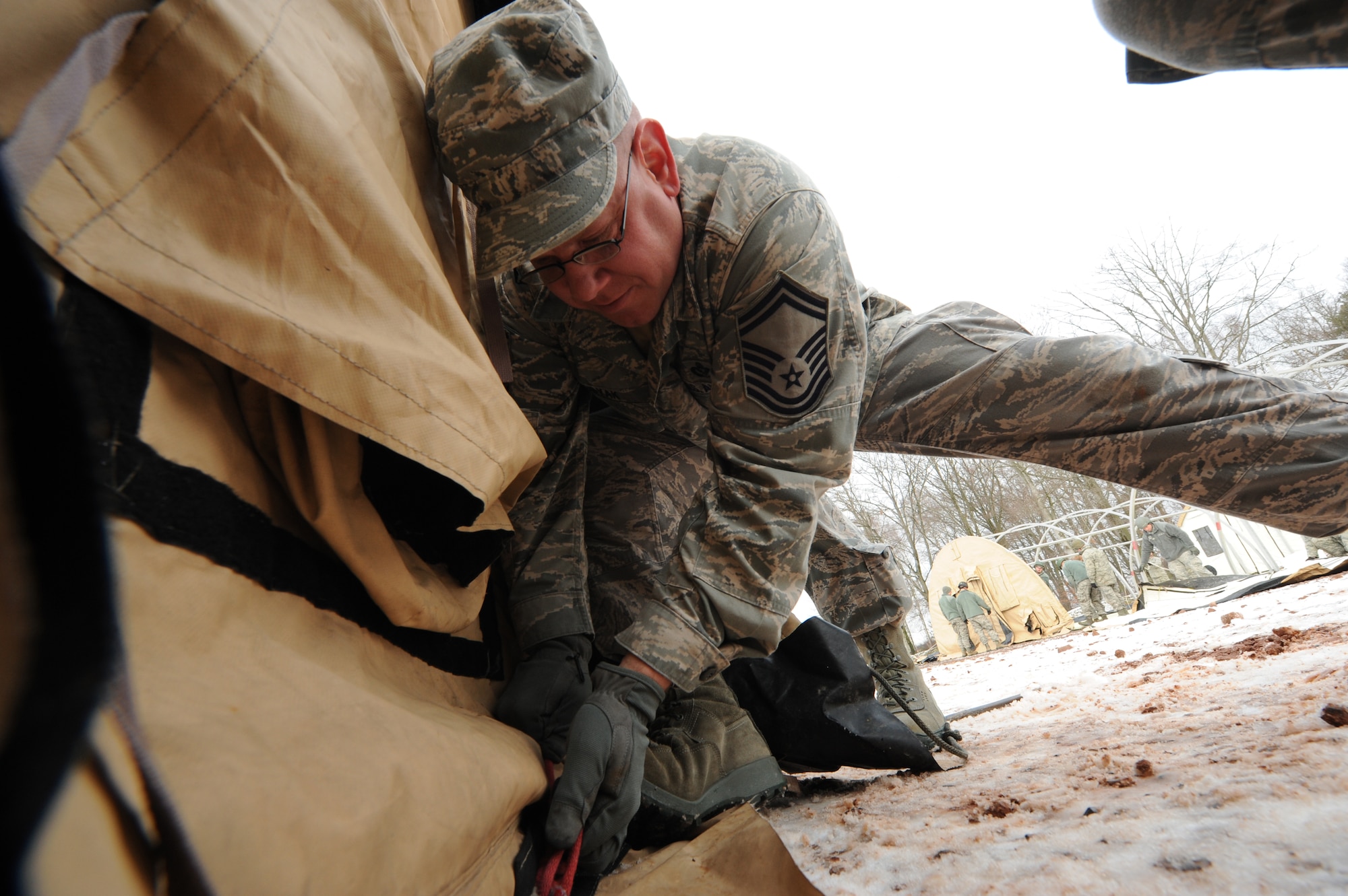 Senior Master Sgt. David Dubyak, 48th Civil Engineer facility superintendent, ties down a cover to a tent during the Silver Flag training exercise, March 5, 2013, Ramstein Air Base, Germany. The purpose of Silver Flag is to prepare Airmen for any type of bare-base deployment. (U.S. Air Force photo/Senior Airman Aaron-Forrest Wainwright)