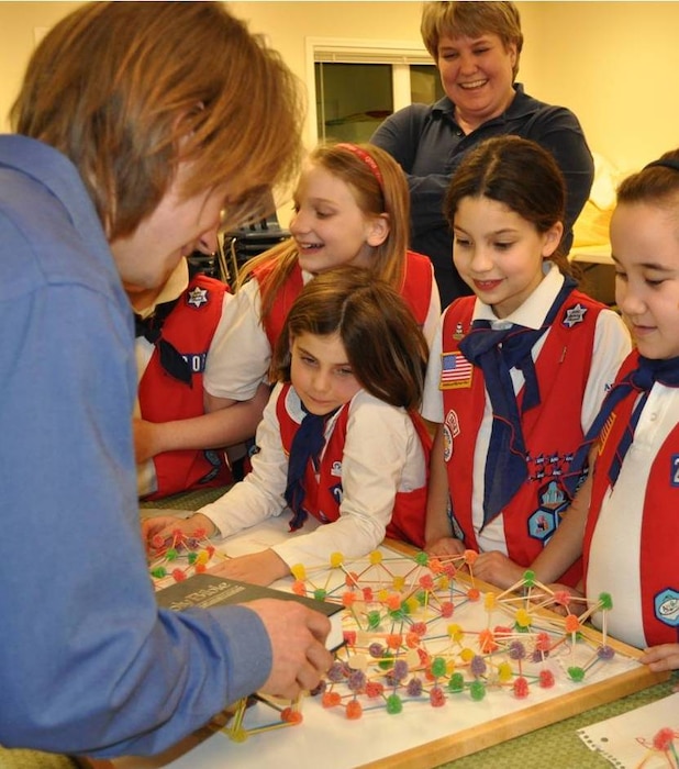 An American Heritage Girls Troop learns about structural integrity using gumdrops and toothpicks. Bo Wycoff, civil engineer, prepares to test toothpick and gumdrop structures built by the girls. Greg Schmidt, deputy chief of the Engineering Division, serves as an adult leader for the troop and helps them earn their engineering merit badge. Schmidt created the badge for the national organization in 2010.