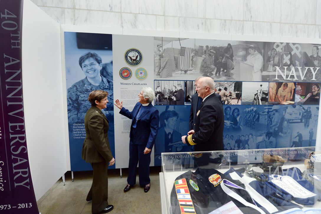 The Rev. Dianna Pohlman Bell, center, points to a photo of Marine Corps Rear Adm. Margaret G. Kibben, front left and pictured left, to Chief of Navy Chaplains Rear Adm. Mark L. Tidd, front right, and Donal Bell, back right, at the new women chaplains exhibit at the Women in Military Service for America Memorial at Arlington, Va., March 4, 2013. The Navy commissioned then Lt. j.g. Dianna Pohlman to serve as the Defense Department's first female chaplain in July 1973. The Air Force and Army followed suit later that year. Kibben was the first woman chaplain for the Marine Corps.