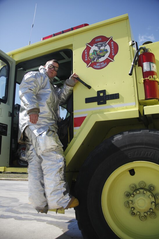 Lance Cpl. Shannon R. Bandy, an aircraft rescue and firefighting specialist with Headquarters and Headquarters Squadron, hangs on to a P-19 crash fire rescue vehicle parked out on the flight line at Marine Corps Air Station Cherry Point Friday. Bandy said she doesn’t take being a firefighter lightly. “From boot camp on, we are taught to take care of the Marines beside you,” she said. “This job gives me the responsibility of saving lives. If I needed to, in an instant I would give up my life to save one of my brothers or sisters to my left and right.”

