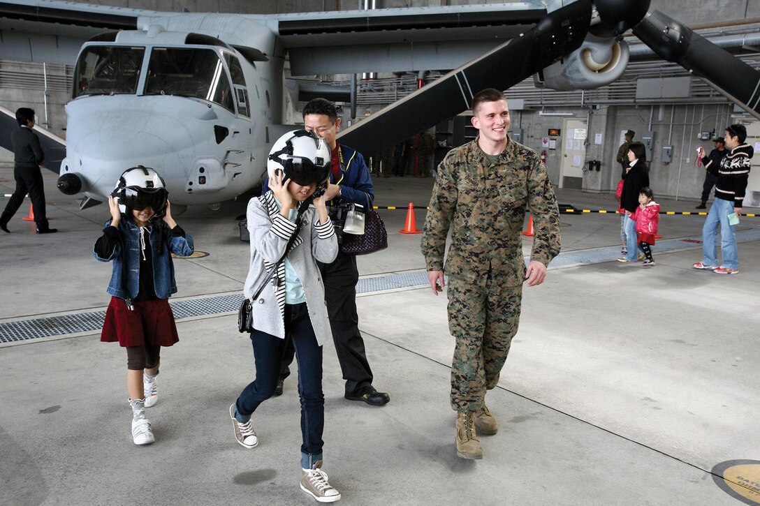 Lance Cpl. Devon B. Springer walks away from an MV-22B Osprey after taking a photo with Okinawa community members during a family day hosted by Marine Medium Tiltrotor Squadron 265 March 3 at Marine Corps Air Station Futenma. The family day was held to familiarize more than 300 parents and children from the community with the aircraft and safety equipment and provide an opportunity to ask questions about the aircraft and its capabilities. Springer is a flight equipment technician with VMM-265, Marine Aircraft Group 36, 1st Marine Aircraft Wing, III Marine Expeditionary Force. 