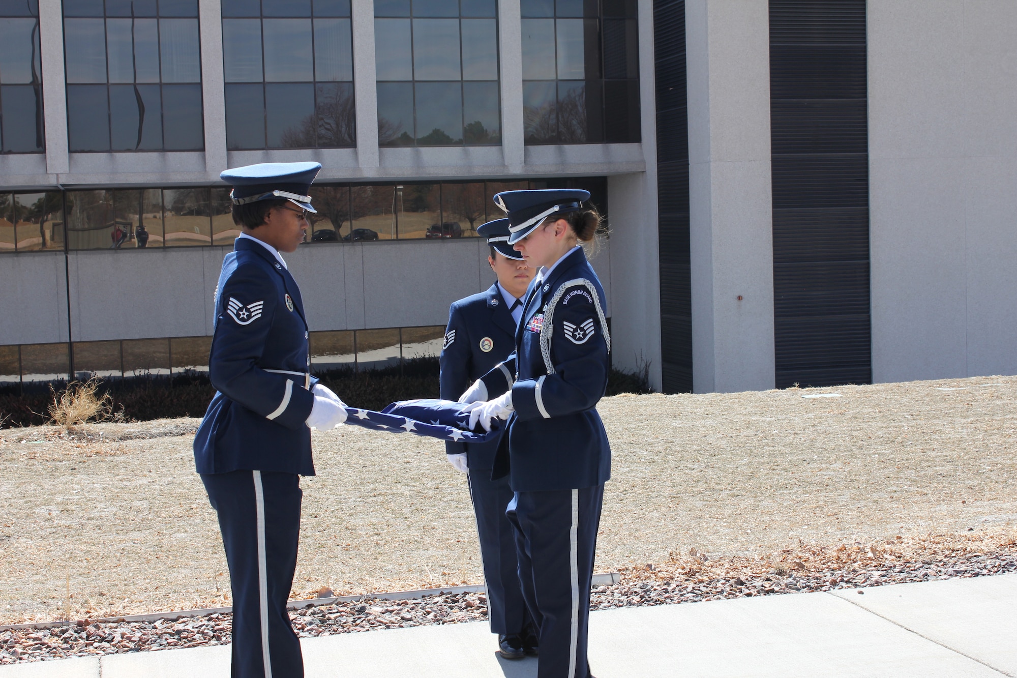Members of the Air Reserve Personnel Center Honor Guard, Staff Sgts. Cindy Rodriguez, Letitia Edwards and Ashley Kidder, folded a U.S. flag after it was flown over the former ARPC building in Denver today. The flag ceremony honored the retirement of the center's 29th commander, Maj. Gen. Eric Crabtree. (U.S. Air Force photo/Cindy Dewey)