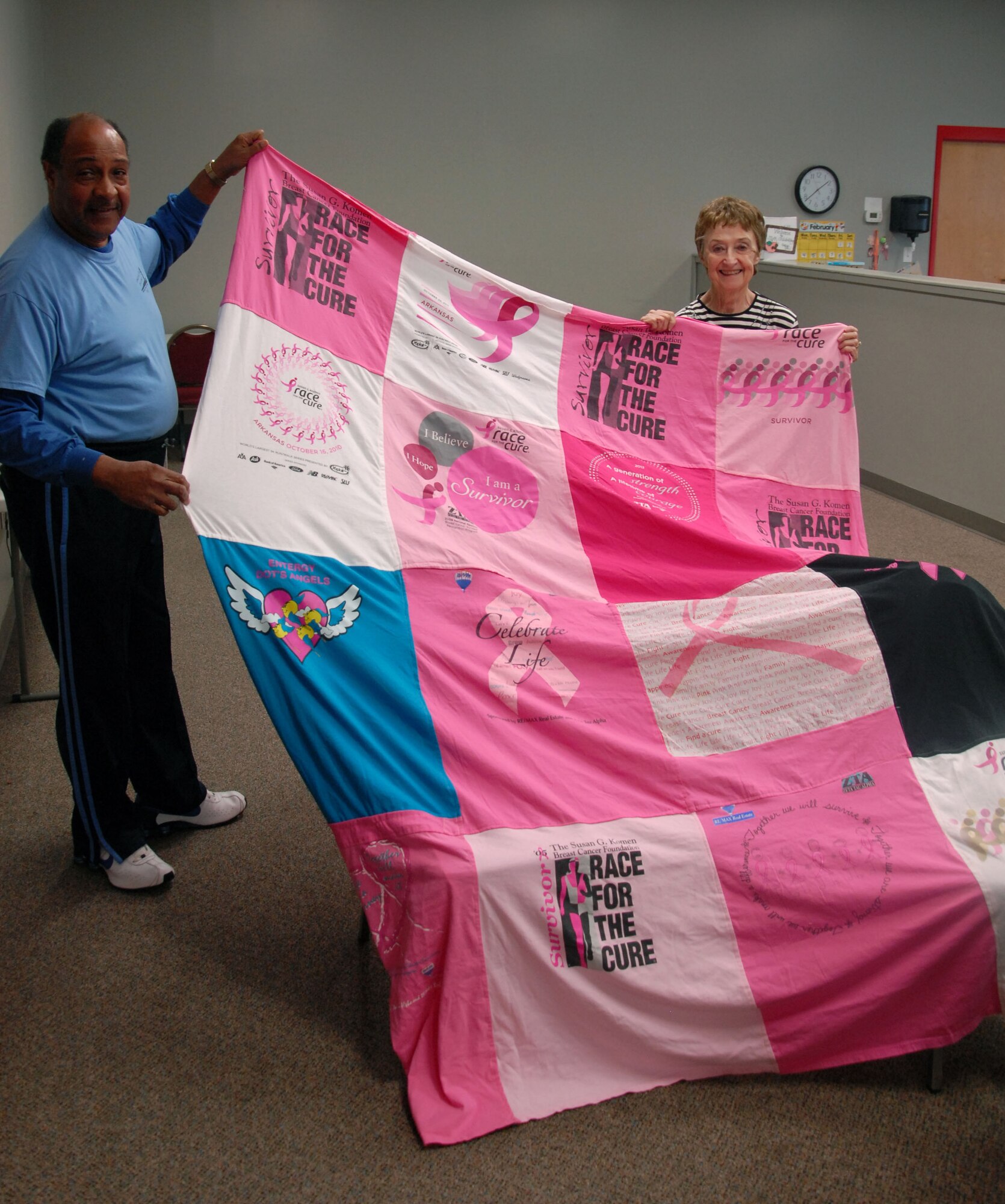 David Gayles, Air Force retiree and husband of the late Jean Gayles, and Pat Evans, retired school teacher, hold one of two blankets made from 11 Race for the Cure breast cancer shirts Feb. 27, 2013, at the Jacksonville Community Center. David Gayles requested Evans make the blankets to honor his wife’s wish. (Photo by Cheri Dragos-Pritchard)