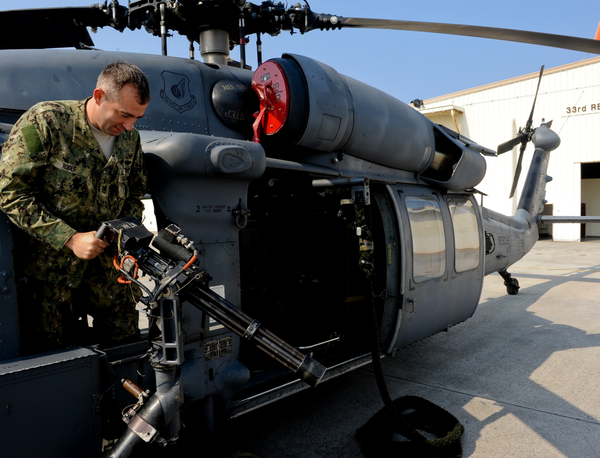 U.S. Navy Command Master Chief Mark Rudes, U.S. Pacific Command senior enlisted leader, handles a mini-gun on an HH-60G Pave Hawk helicopter on Kadena Air Base, Japan, March 6, 2013. Rudes was given a detailed tour of the helicopter during his visit to the flight line and was given an explanation on some of the different functions of the aircraft. (U.S. Air Force photo/Airman 1st Class Justin Veazie)