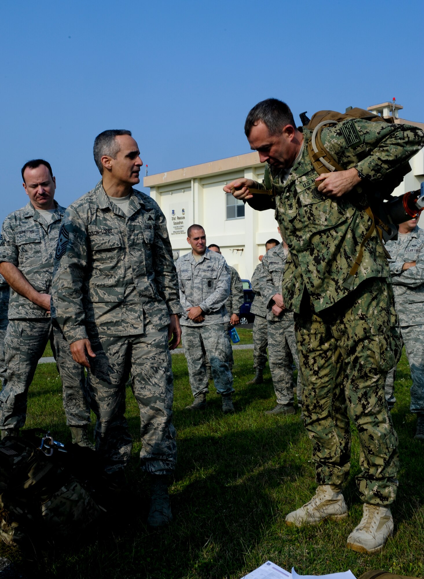U.S. Air Force Chief Master Sgt. Ramon Colon-Lopez, 18th Wing command chief, helps U.S. Navy Command Master Chief Mark Rudes, U.S. Pacific Command senior enlisted leader, with a pararescueman ruck sack during a vehicle extrication demonstration on Kadena Air Base, Japan, March 6, 2013. Rudes wanted to see what was expected of pararescuemen first hand. (U.S. Air Force photo/Airman 1st Class Justin Veazie)