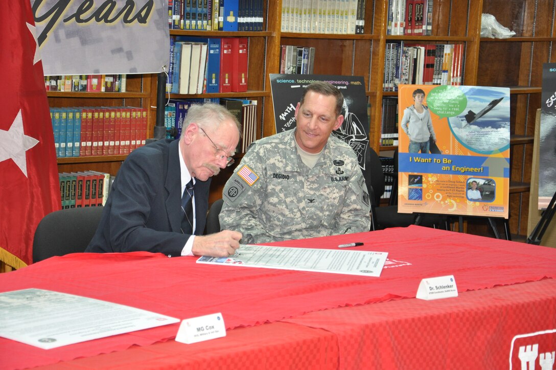 Col. Donald Degidio, commander of the U.S. Army Corps of Engineers Far East District, watches as Dr. Richard Schlenker, Department of Defense Schools Korea District science, technology, engineering, and mathematics (STEM) coordinator, signs an education partnership agreement March 7.  The partnership between USACE and DoDDS Korea District will center on support for the STEM initiative.  (Photo by Patrick Bray)