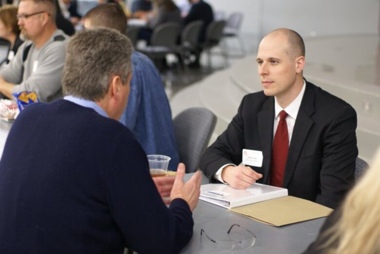 Adam Crisp, programs and project management division, speaks to a business representative during the Meet the Corps Day event.