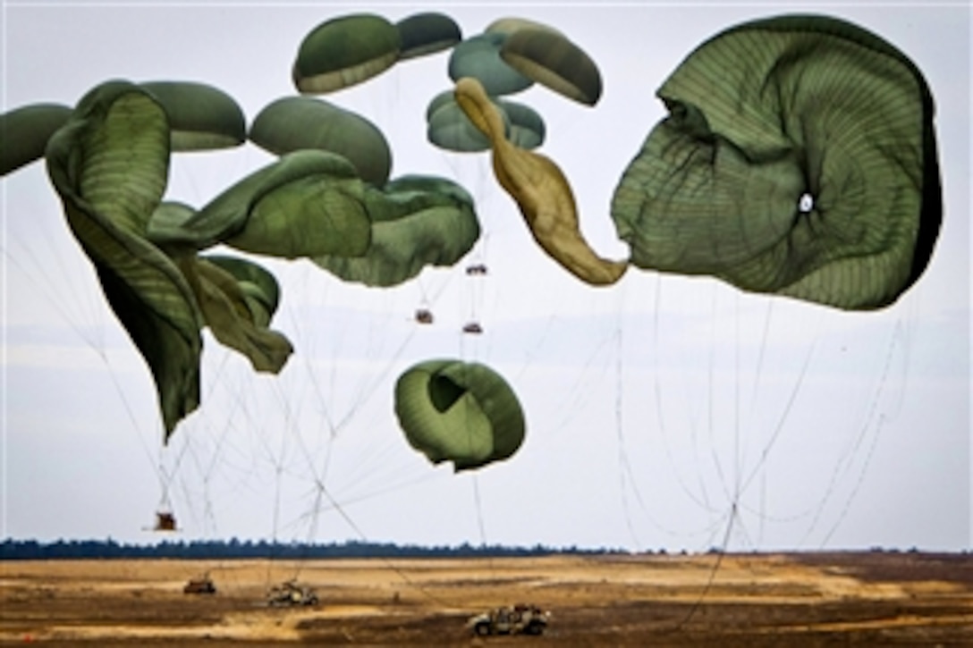 Giant parachutes collapse as their load of Humvees hit the ground during a joint operational access exercise on the Sicily drop zone at Fort Bragg, N.C., on Feb. 25, 2013.  Paratroopers will descend once the heavy equipment is safely on the ground.  The exercise enhances cohesiveness between U.S. Army, Air Force and allied personnel, allowing the services an opportunity to properly execute large-scale heavy equipment and troop movement