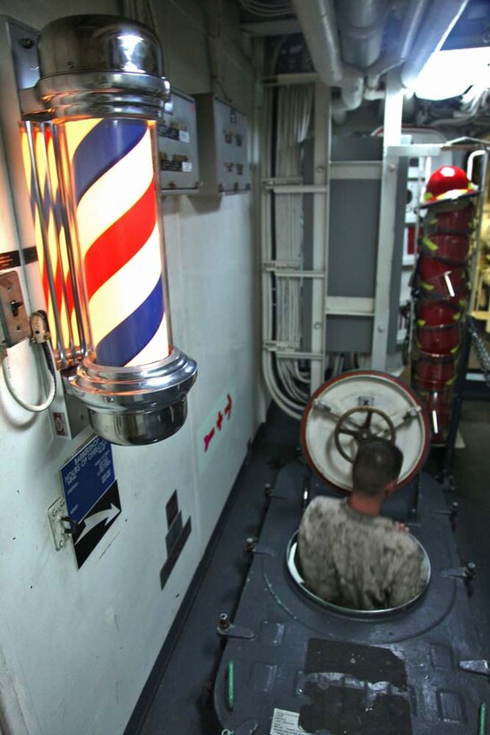 A Marine assigned to the 15th Marine Expeditionary Unit walks down into the barbershop aboard the USS Rushmore to get a haircut, March, 7. While deployed, Marines practiced and honed the valuable skill of cutting hair taking the place of civilian barbers. The 15th MEU is deployed as part of the Peleliu Amphibious Ready Group as a U.S. Central Command theater reserve force, providing support for maritime security operations and theater security cooperation efforts in the U.S. 5th Fleet area of responsibility. (U.S. Marine Corps photo by Cpl. Timothy R. Childers/Released)
