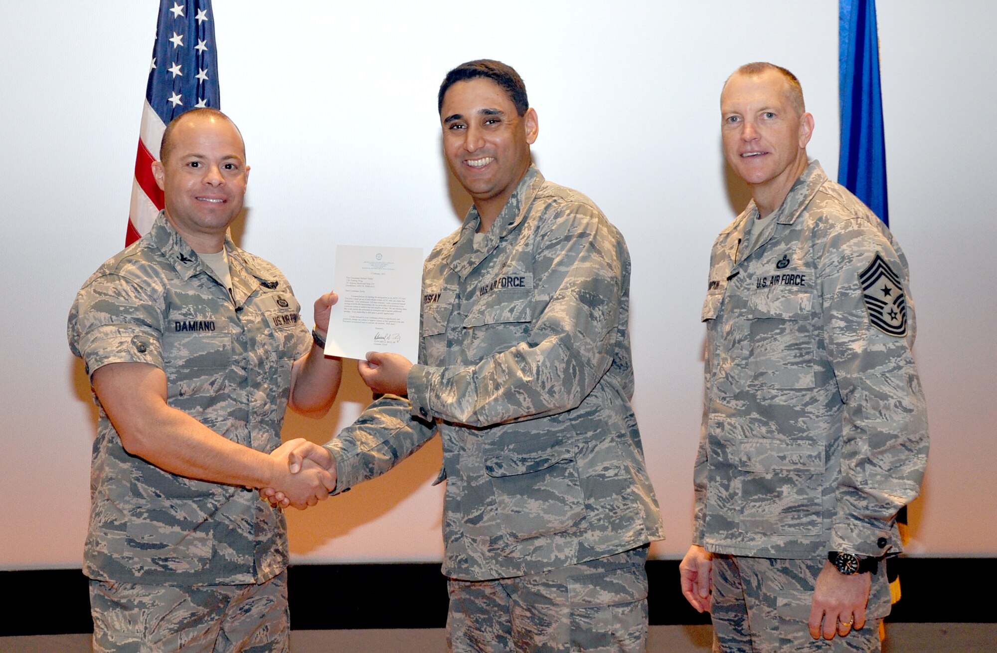 GOODFELLOW AIR FORCE BASE, Texas—Col. Mark Damiano, 17th Training Wing Commander, presents the Air Education and Training Command Cost Conscious Culture Ace award to 1st Lt. Michael Tesfay, 17th Medical Support Squadron, during the 17th TRW Commander’s Call at the base theater, March 7. (U.S. Air Force photo/1st Lt. Leanne Hedgepeth) 