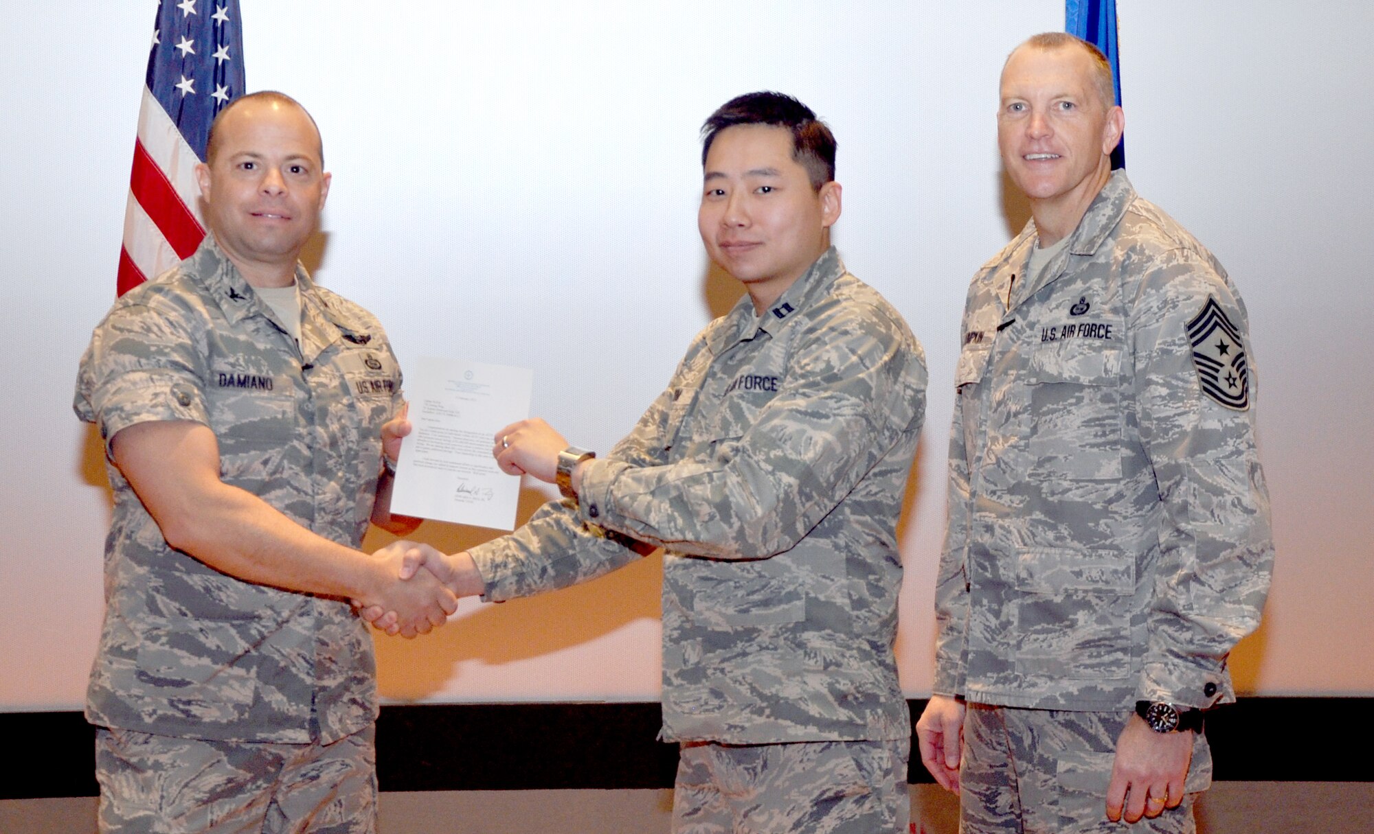 GOODFELLOW AIR FORCE BASE, Texas—Col. Mark Damiano, 17th Training Wing Commander, presents the Air Education and Training Command Cost Conscious Culture Ace award to Capt. Jin Kim, 17th Medical Group, during the 17th TRW Commander’s Call at the base theater, March 7. (U.S. Air Force photo/1st Lt. Leanne Hedgepeth) 