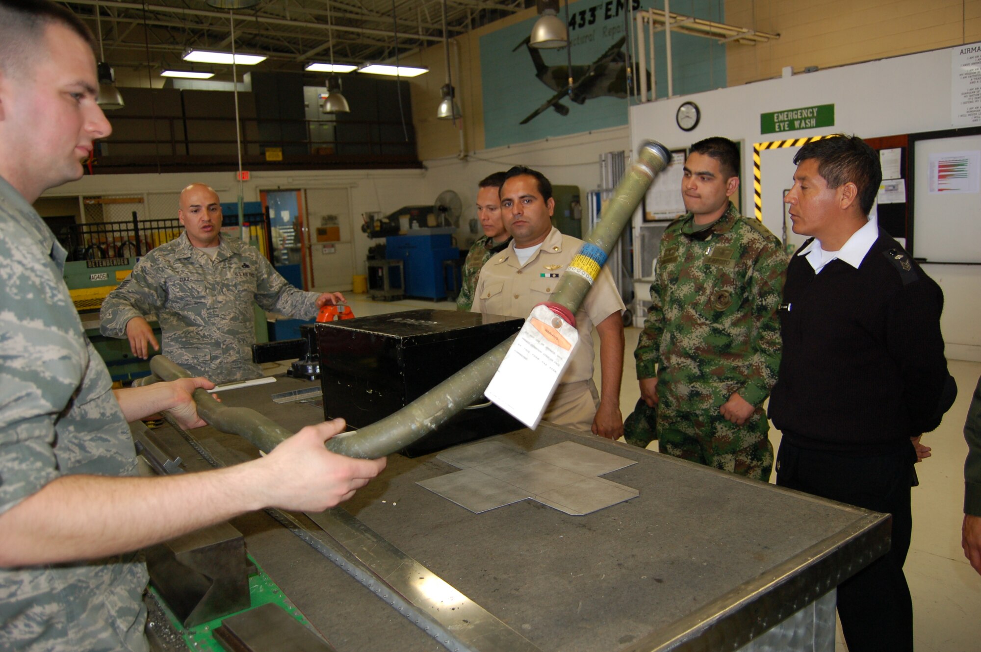 Airman 1st Class Alfred Hoefer, sheet metals mechanic for the 433rd Airlift Wing's Structural Repair shop, demonstrates a length of metal tubing with the shop's metals-tubing bender machine.  Demonstration was done for 21 visiting students from the Inter-American Air Forces Academy, located at Joint Base San Antonio-Lackland.  These IAAFA students are enrolled in the school's ten-week Aircraft Maintenance Management course. (U.S. Air photo by Elsa Martinez)