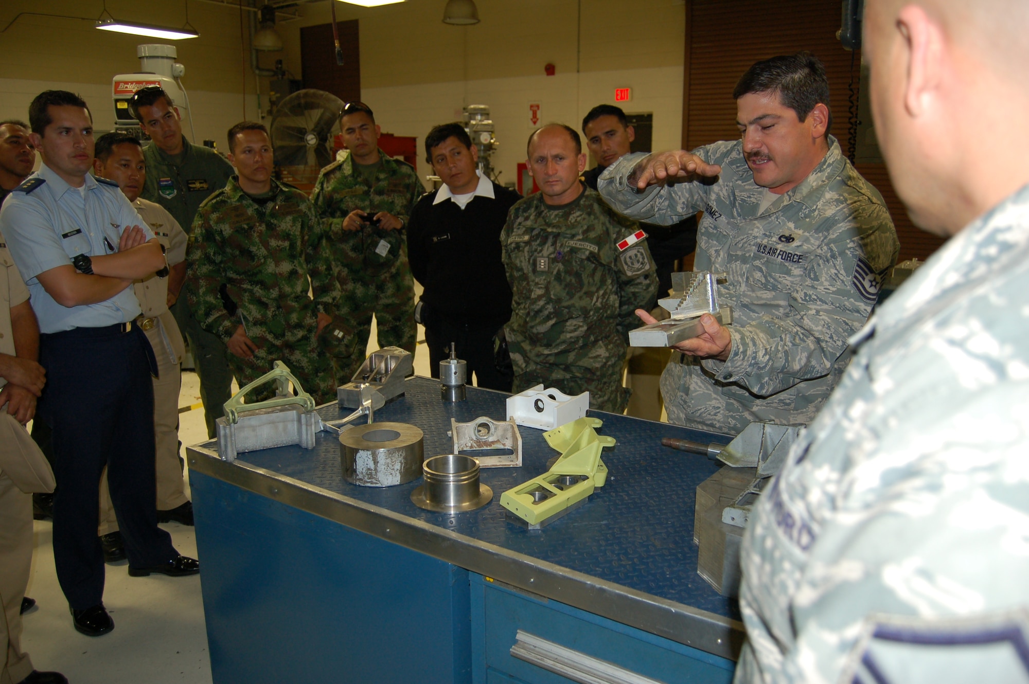 Tech. Sgt. James Gomez, an aircraft metals technician with the 433rd Airlift Wing's Metals Technology shop, displays a variety of C-5A Galaxy components manufactured by the shop as replacements for the 433rd AW C-5A Galaxy fleet.  Twenty-one students from the Inter-American Air Forces Academy are enrolled in the  Aircraft Maintenance Management course.   Upon completion, students return to their respective countries to apply their instruction to their assigned aircraft fleet.  (U.S. Air Force photo by Elsa Martinez)