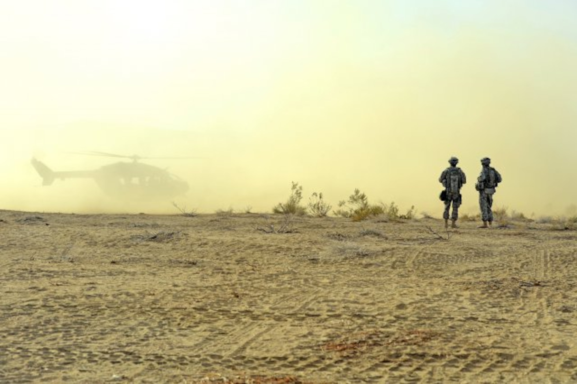 Soldiers of the 2nd Armored Brigade Combat Team, 1st Infantry Division, watch a Kiowa helicopter land in the desert dust at the National Training Center, Fort Irwin, Calif., Feb. 21, 2013. Aviators and acquisition officials are exploring sensors, queing and control methods to better enable flying and landing in what is called a "degraded visual environment." (U.S. Army photo by E.J. Hersom)