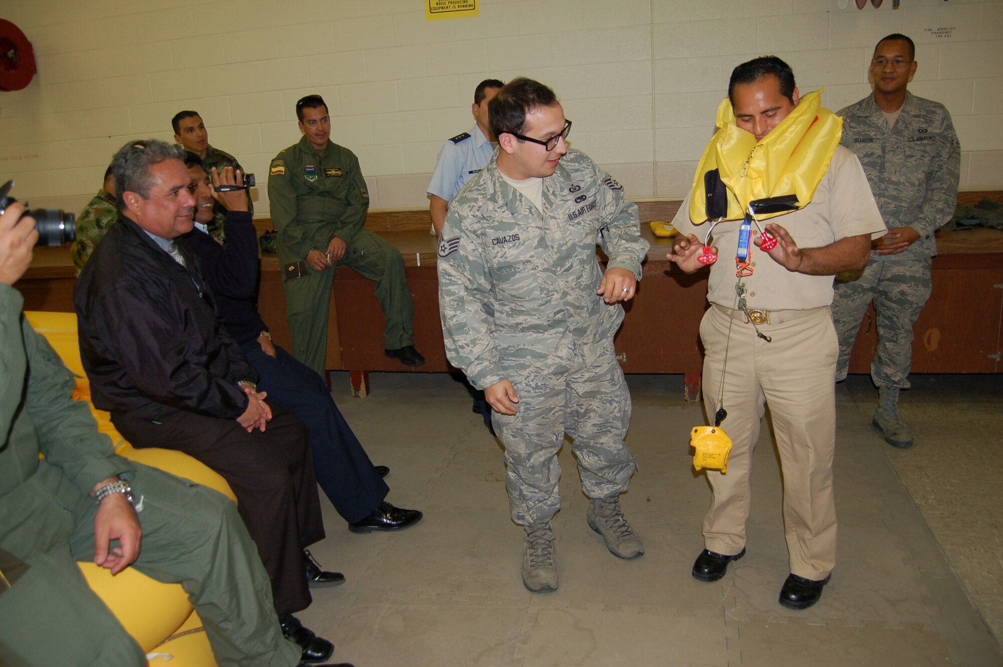 Staff Sgt. John Cavazos, aircrew flight equipment technician at the 433rd AW Survival Shop, demonstrates an inflatable life preserver to 21 students of the Inter-American Air Forces Academy who visited the wing's C-5A maintenance shops on March 7. Located at Joint Base San Antonio-Lackland, IAAFA conducts international training in Spanish, forging ties with Latin American military, national police and other governmental agencies.  (U.S. Air Force photo by Elsa Martinez)