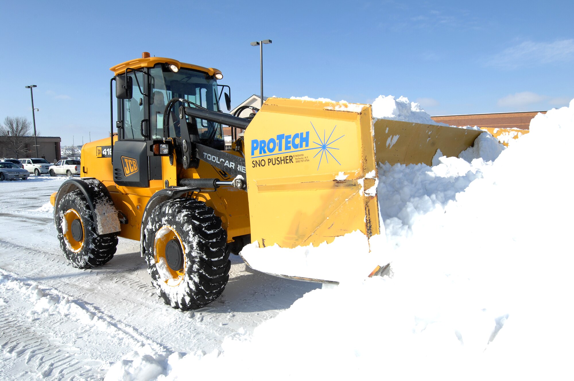 Jim Funkhouser, an airfield clearing operator from the 55th Civil Engineering Squadron, operates a front-end loader with a pusher blade to clear snow from the parking lot of the Base Exchange at Offutt Air Force Base, Neb., Feb. 22. Offutt received eight inches of accumulation with the storm. (U.S. Air Force photo by Delanie Stafford/Released)