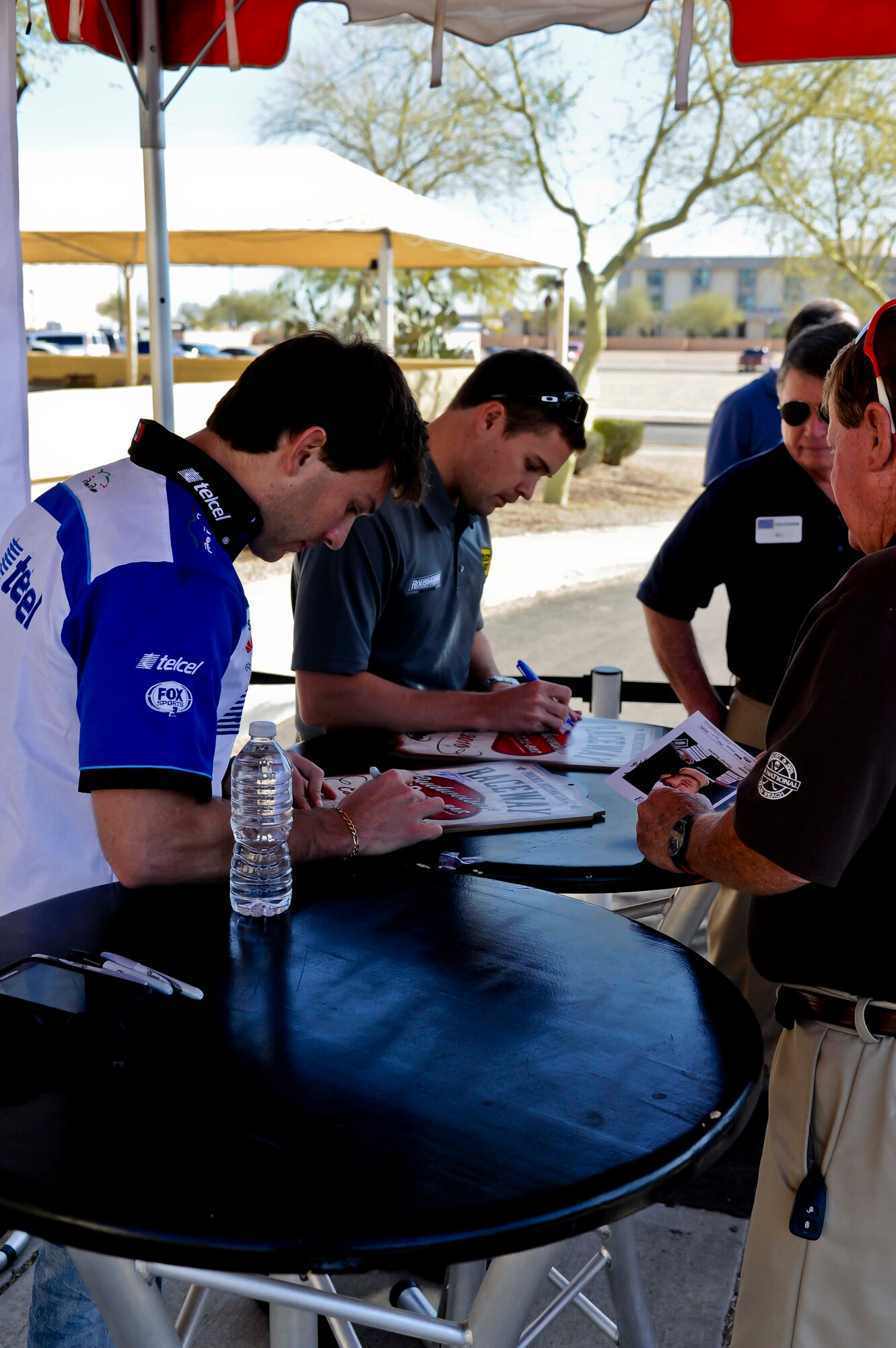 FROM LEFT: Daniel Suarez and Ricky Stenhouse Jr. sign NASCAR memorabilia Feb. 28 during a visit to the base. The two drivers signed autographs, posed for photos and talked with service members during a meet and greet arranged by the USO. (U.S. Air Force photo/Staff Sgt. C.J. Hatch)