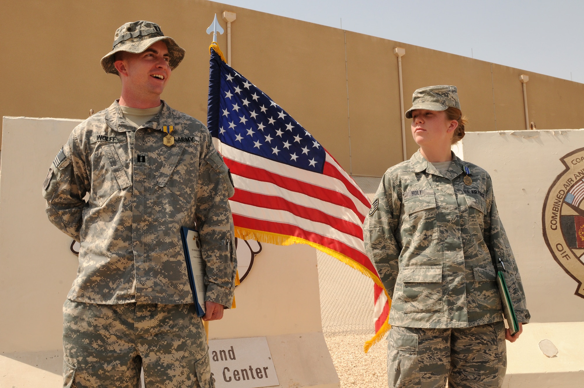 U.S. Army Capt. Nicholas Wolff, the Army Air Defense operations officer for the 32nd Army Air and Missile Defense Command combat ops division, speaks to an audience after receiving the U.S. Air Force Commendation Medal, March 1, at a deployed location in Southwest Asia. Next to him is Air Force Staff Sgt. Lindsay Holt, from U.S. Air Forces Central Command’s A6 section, who was awarded the Army Achievement Medal for her contributions to the successful completion of Exercise Fast Eagle II. (U.S. Air Force photo/Tech. Sgt. Mike Andriacco)