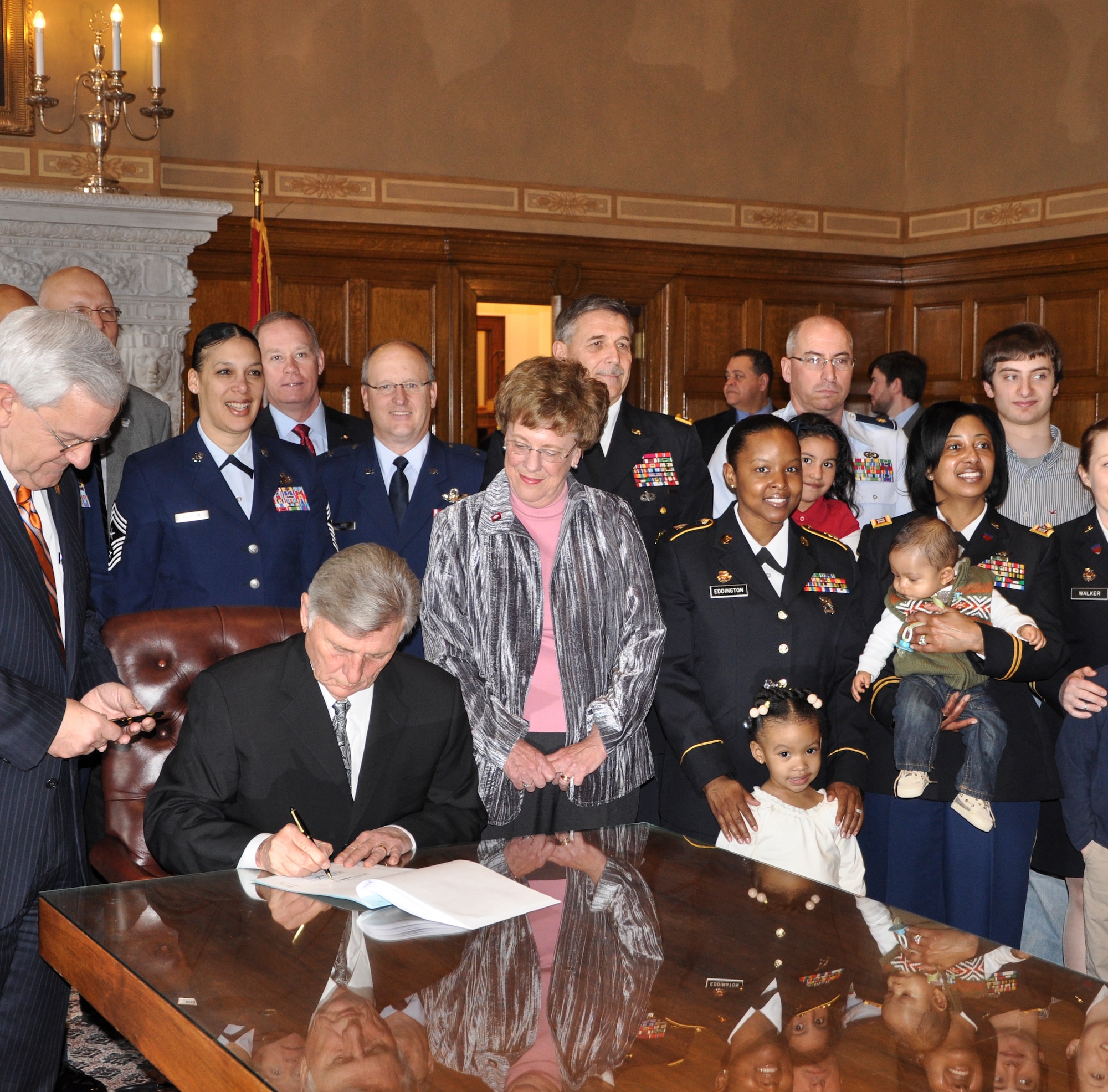 Military families watch Arkansas Governor Mike Beebe sign a new education bill March 5, 2013, in Little Rock, Ark. The newly adopted Interstate Compact on Educational Opportunity for Military Children eases transitions for military children who frequently move because of their families’ service. (U.S. Air Force photo by 1st Lt. Mallory Glass)