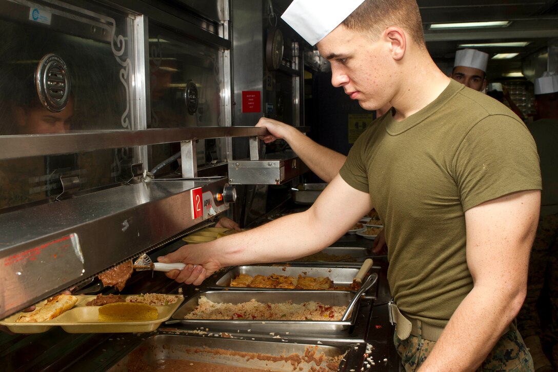 Lance Cpl. Ben P. Moore, a field radio operator with Battalion Landing Team 1st Battalion, 5th Marine Regiment, 31st Marine Expeditionary Unit, and a native of Lufkin, Texas, gives a Marine a scoop of refried beans during an afternoon meal here, Feb. 5. More than 2,000 Marines and Sailors on the USS BHR line up outside the mess areas to receive their daily rations of hot food. The mess crew cooks 42,000 servigs worth of food for five dishes to complete the four meals served each day. The crew also prepares desserts, assortments of fruit, and cold and hot drinks. The 31st MEU is the only continuously forward-deployed MEU and is the Marines Corps' force in readiness in the Asia-Pacific region.
