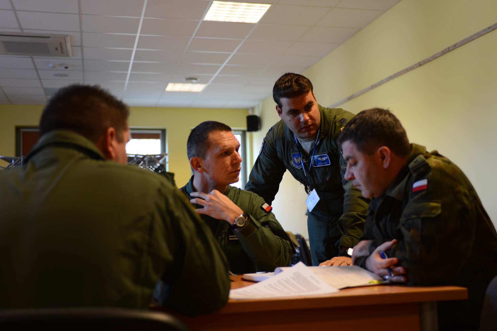 POWIDZ AIR BASE, Poland —U.S. Air Force Capt. Austin Rust, 37th Airlift Squadron, Ramstein Air Base, Germany discusses an air drop mission with Polish air force Maj. Miroslaw Jakubowski, (left) C-130/M-28 Transportation Squadron deputy commander (center) Maj. Jaroslaw Kotonowicz, air traffic control tower commander and U.S. Air Force Capt. Jarrod Jones, a 37th AS pilot, during Exercise Screaming Eagle V, March 5, 2013. Screaming Eagle V is hosted by Aviation Detachment 1, 52nd Operations Group, Lask Air Base, Poland, in support of NATO Article 5. The Av-Det's presence in Poland demonstrates the United States' enduring partnership with Poland. (U.S. Air Force photo/Tech. Sgt. Kenya Shiloh) (released) 