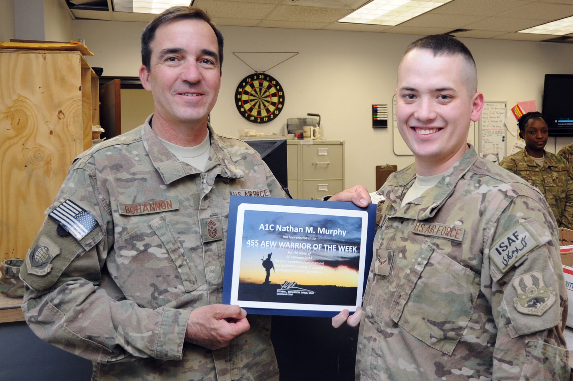 Chief Master Sgt. Steve Bohannon, Command Chief Master Sergeant of the 455th Air Expeditionary Wing, presents the "Warrior of the Week" award to Airman 1st Class Nathan Murphy, 455th Expeditionary Logistics Readiness Squadron customer service technician, on Bagram Airfield, Afghanistan, March 6, 2013. Murphy supports 151 supply accounts across Bagram and 19 forward operating bases. (U.S. Air Force photo/Staff Sgt. David Dobrydney)
