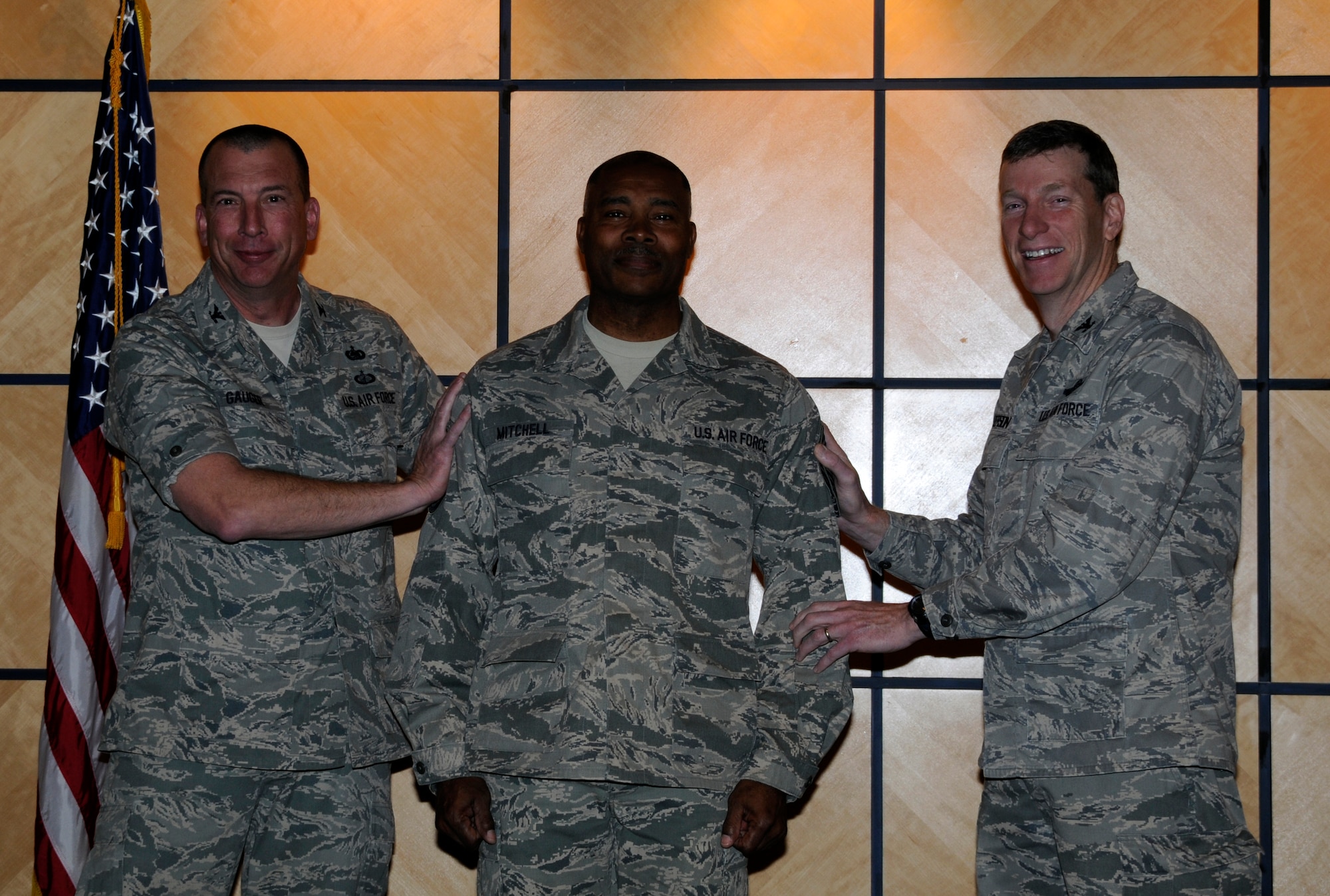 Col. Pete Gauger, 188th Fighter Wing vice commander, left, and Col. Mark Anderson 188th Fighter Wing commander, right, tack on chief master sergeant chevrons on Kerry Mitchell, who was elevated to E-9 during a promotion ceremony at the 188th March 2. (National Guard photo by Senior Airman Hannah Landeros/188th Fighter Wing Public Affairs)

