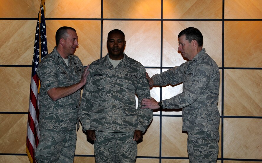 Col. Pete Gauger, 188th Fighter Wing vice commander, left, and Col. Mark Anderson 188th Fighter Wing commander, right, tack on chief master sergeant chevrons on Kerry Mitchell, who was elevated to E-9 during a promotion ceremony at the 188th March 2. (National Guard photo by Senior Airman Hannah Landeros/188th Fighter Wing Public Affairs)

