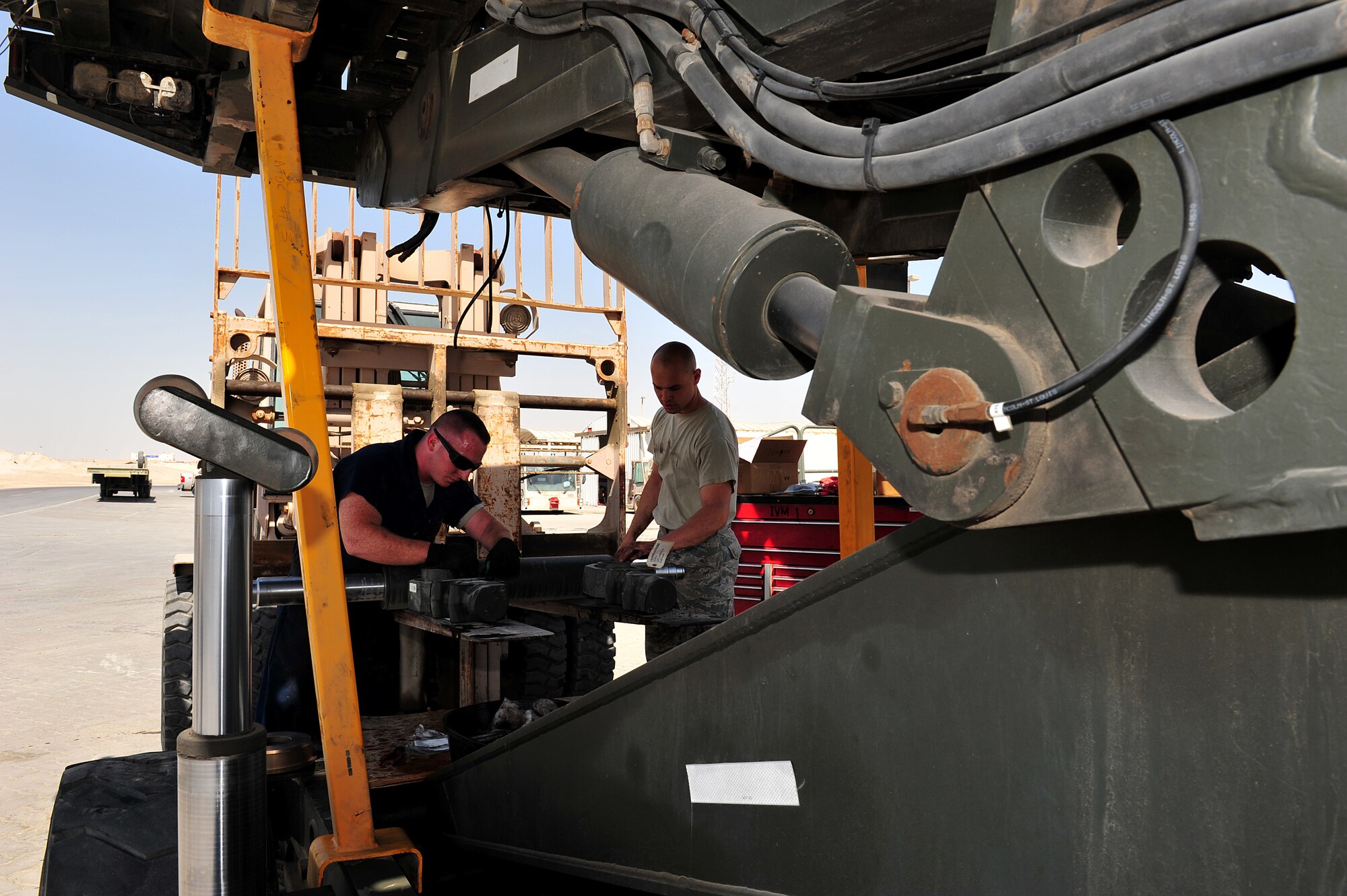 U.S. Air Force Staff Sgt. Joseph Leitch, 380th Logistics Readiness Squadron special material handling equipment craftsman, and Airman 1st Class Travis Martin, 380 LRS vehicle maintenance journeyman, replace the side shift and roll cylinder on a 25K Next Generation Small Loader at an undisclosed location in Southwest Asia Mar. 5, 2013. The vehicle maintenance shop service and repair more than 500 vehicles each month. Leitch is deployed from McGuire Air Force Base, N.J. and Martin is deployed from Cannon AFB, N.M. (U.S. Air Force photo by Tech. Sgt. Christina M. Styer/Released) 