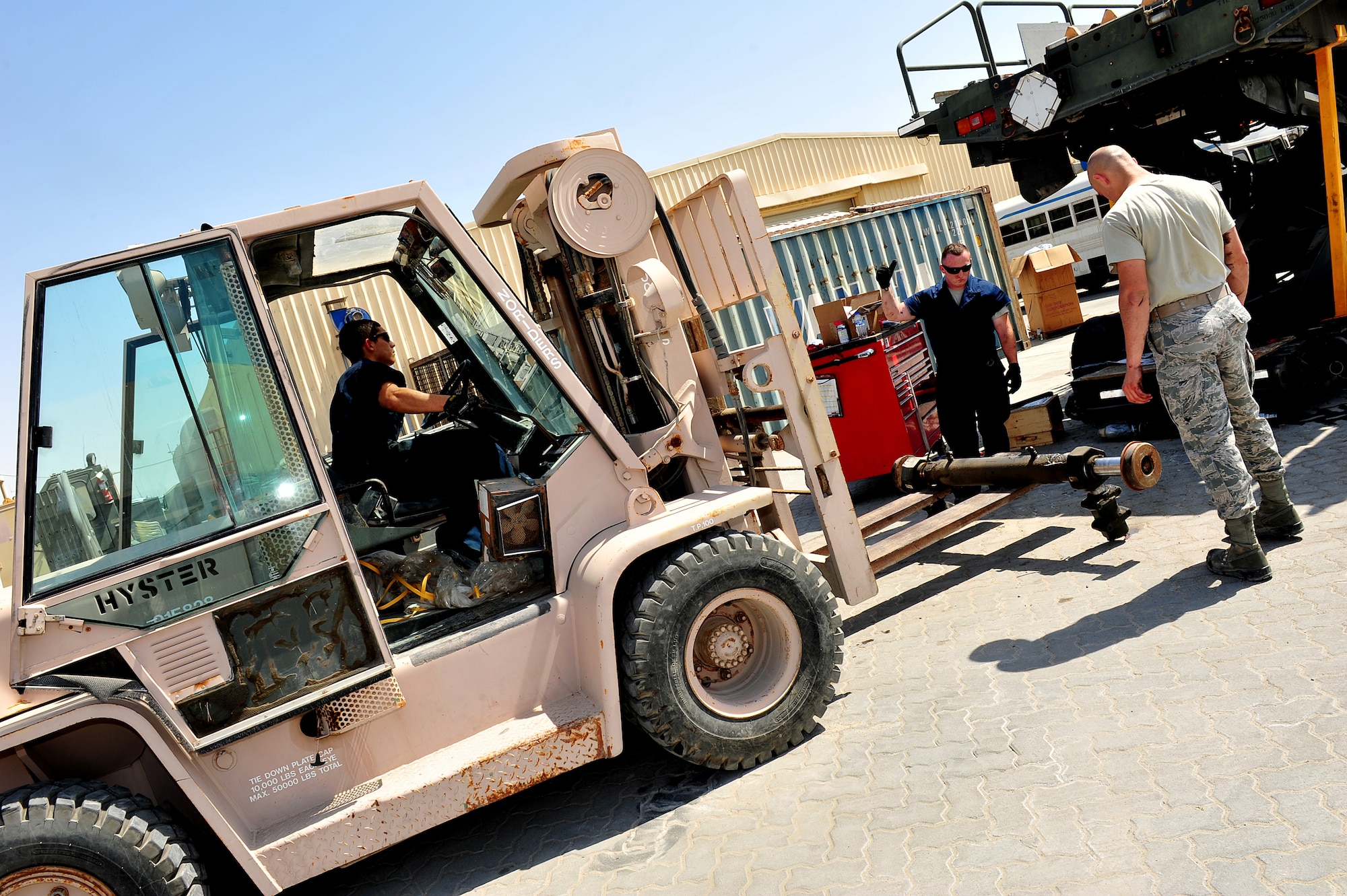 U.S. Air Force Staff Sgt. Joseph Leitch, 380th Logistics Readiness Squadron special material handling equipment craftsman, and Airman 1st Class Travis Martin, 380 LRS vehicle maintenance journeyman, marshal Airman 1st Class Gabriel Ignacio, 380 LRS special material handling equipment journeyman, as they replace the side shift and roll cylinder on a 25K Next Generation Small Loader at an undisclosed location in Southwest Asia Mar. 5, 2013. The vehicle maintenance shop service and repair more than 500 vehicles each month. Leitch is deployed from McGuire Air Force Base, N.J. and Martin and Ignacio are deployed from Cannon AFB, N.M. (U.S. Air Force photo by Tech. Sgt. Christina M. Styer/Released) 