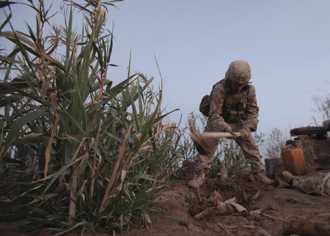 Lance Cpl. Gavin Ellis uses a pick ax to dig up the ground outside a compound suspected of housing insurgents near Patrol Base Boldak March 3. Ellis was searching for any evidence or signs of illegal activity. (Photo by Sgt. Bobby J. Yarbrough)