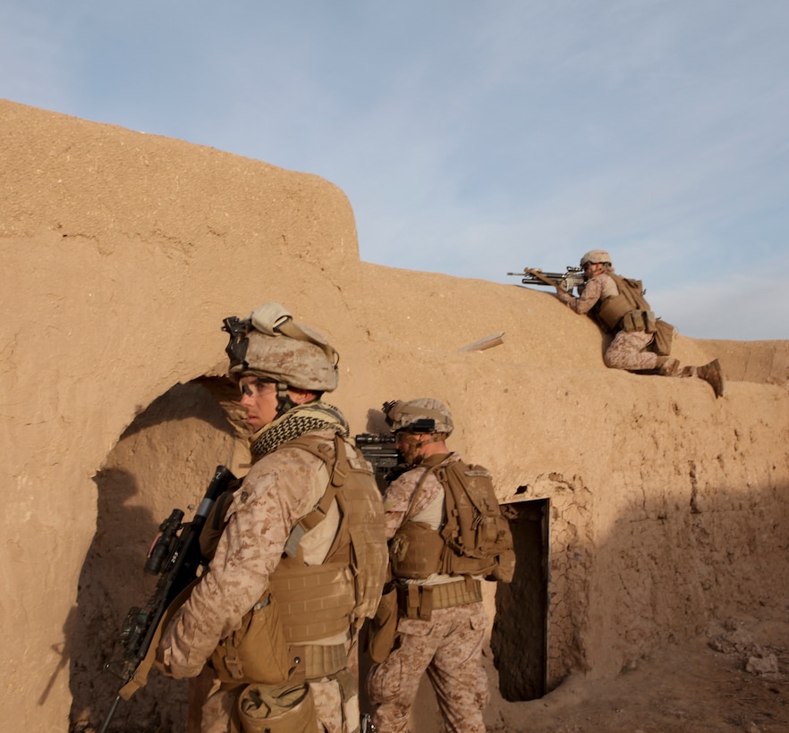 Lance Cpl. Emilio TherienGonzales climbs on the top of a compound to try and locate a shooter who fired on the Marines from an adjacent compound near Patrol Base Boldak March 3. (Photo by Sgt. Bobby J. Yarbrough)
