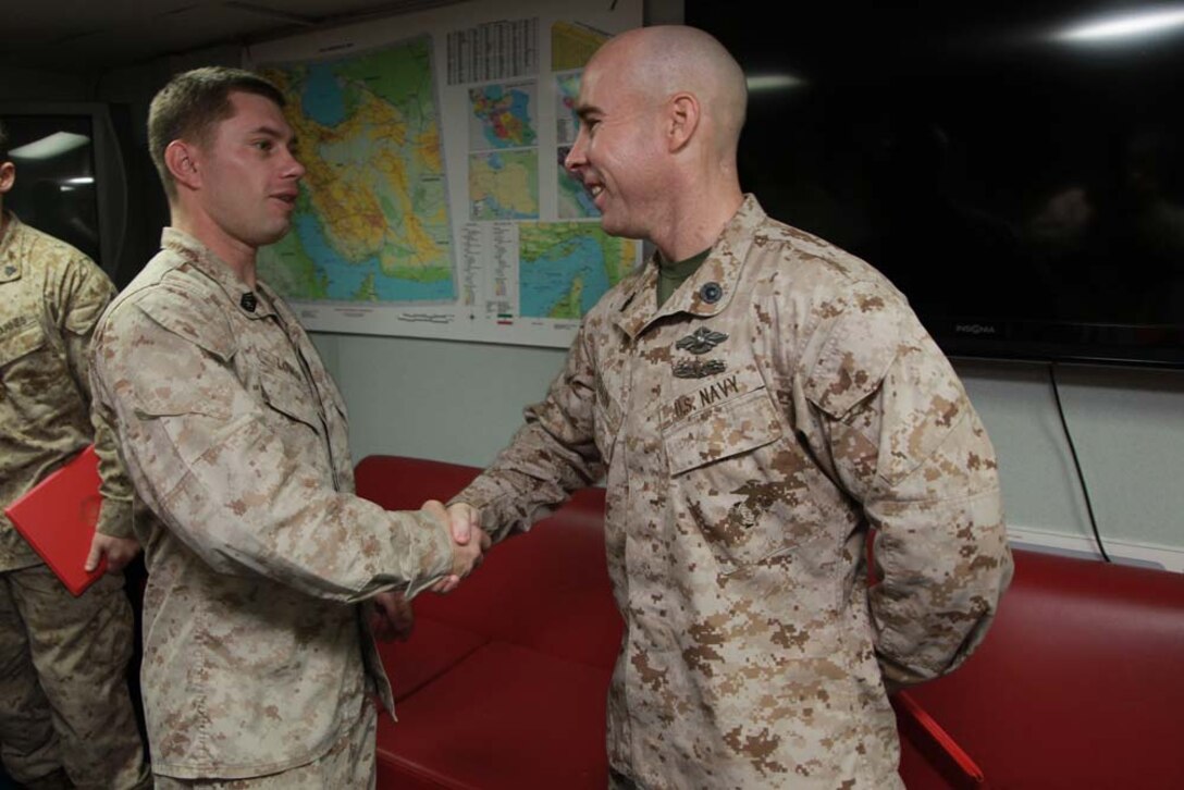 Religious Program Specialist 1st Class Edward S. Debaun, shakes hands with Gunnery Sgt. Robert L. Lower, fires chief, both with Command Element, 15th Marine Expeditionary Unit, after Debaun received a Navy and Marine Corps Achievement Medal aboard USS Peleliu, March 6. The 15th MEU is deployed as part of the Peleliu Amphibious Ready Group as a U.S. Central Command theater reserve force, providing support for maritime security operations and theater security cooperation efforts in the U.S. 5th Fleet area of responsibility. Debaun, 35, is from Copperopolis, Calif., and Lower, 31, is from Laporte, Ind. (U.S. Marine Corps photo by Cpl. John Robbart III)